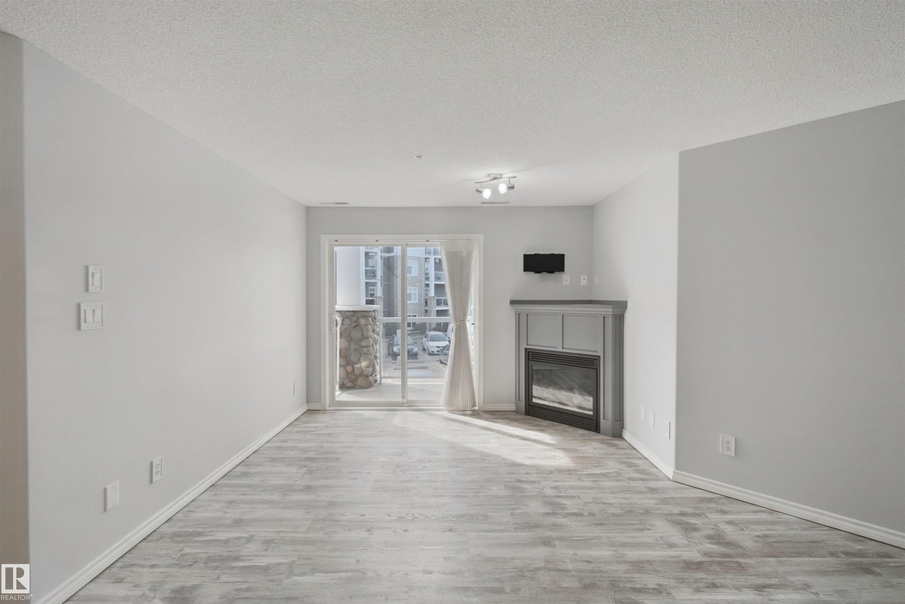 Light gray walls with wood-finish flooring - #208 16035 132 St Nw, Edmonton, AB