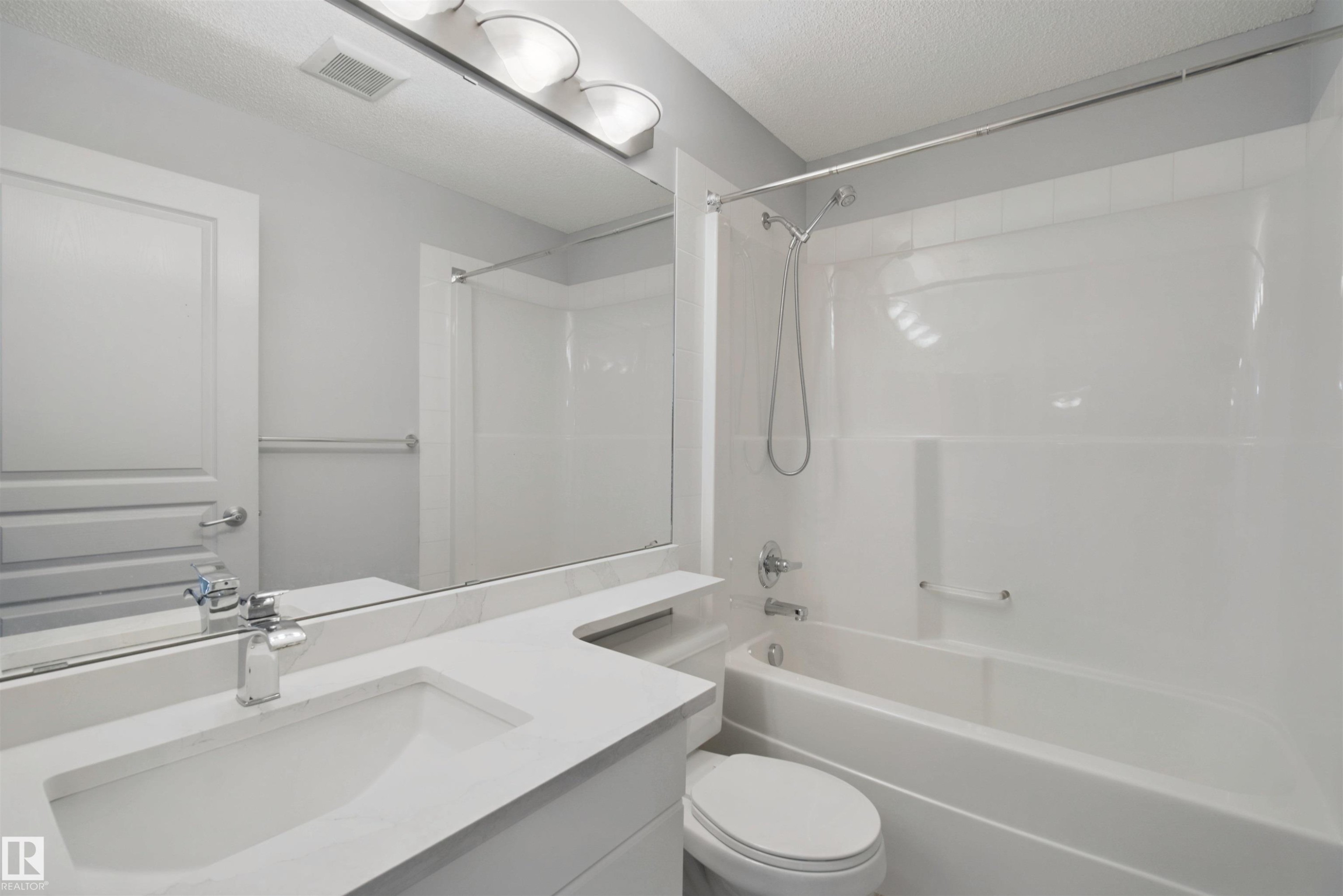 Vanity with integrated sink, chrome faucet, and expansive mirror - #208 16035 132 St Nw, Edmonton, AB
