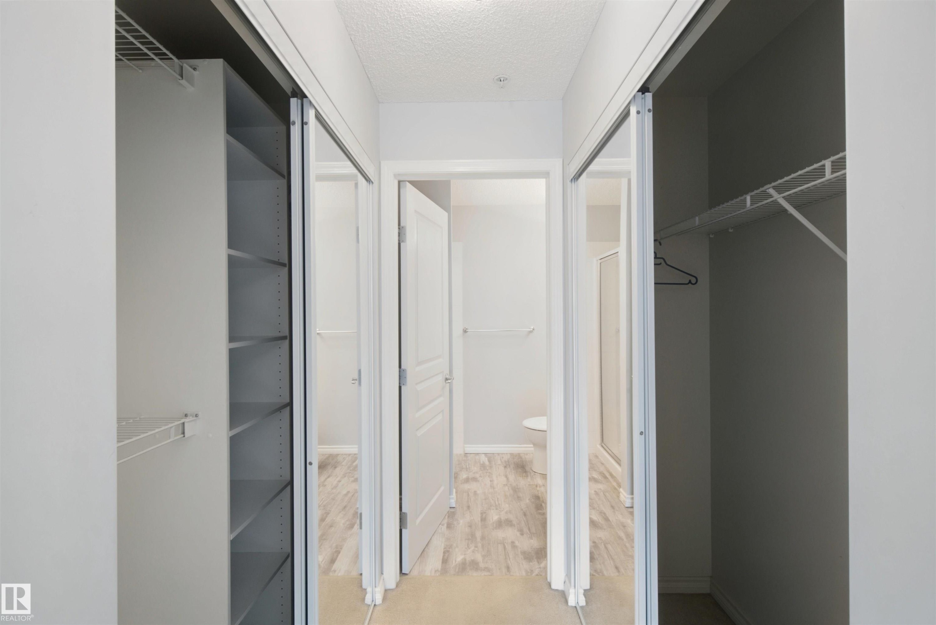 Sliding closet doors with shelving, wire rack storage, and wood-finish flooring - #208 16035 132 St Nw, Edmonton, AB