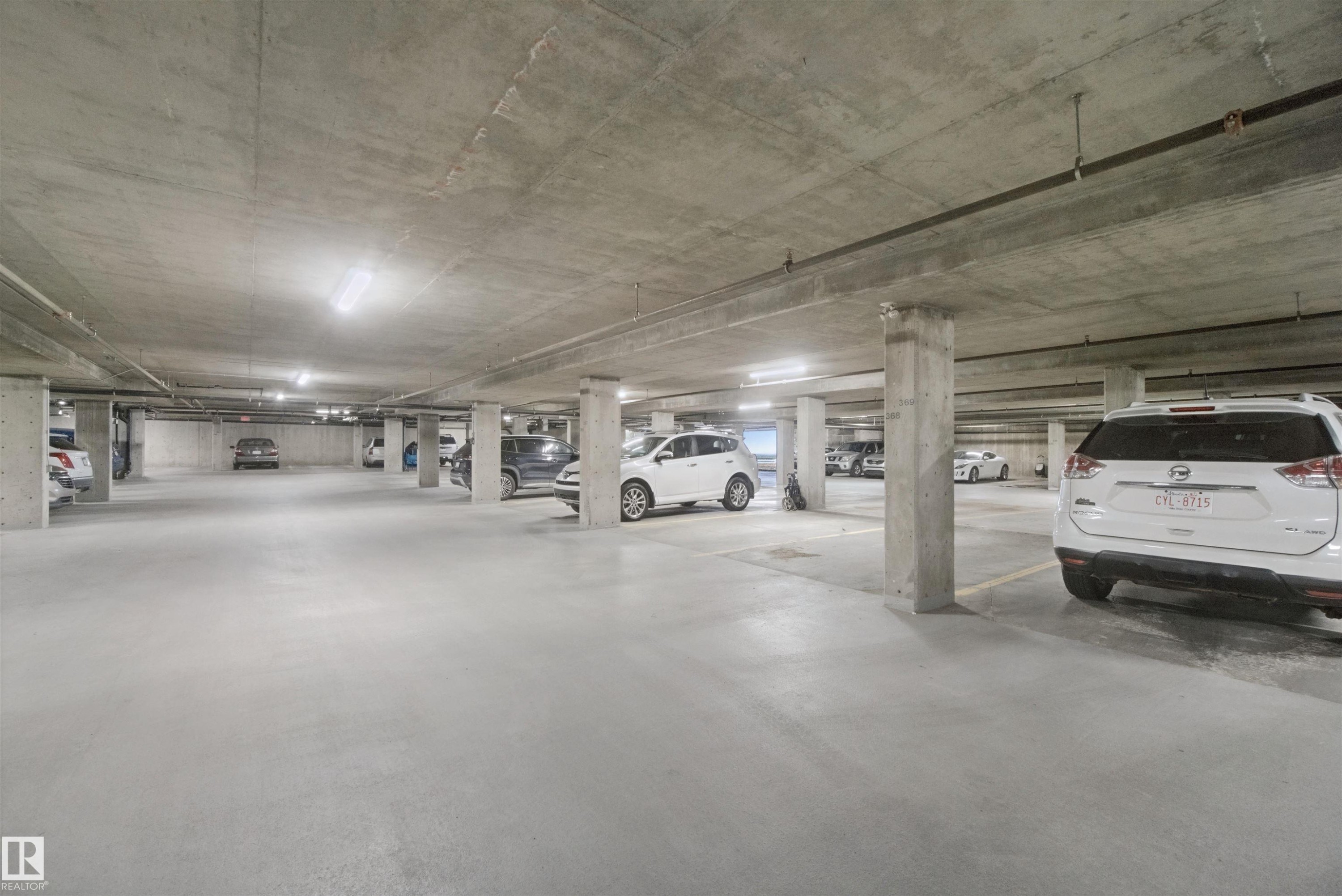Underground parking area featuring concrete flooring, concrete columns, concrete ceiling, and integrated lighting - #208 16035 132 St Nw, Edmonton, AB