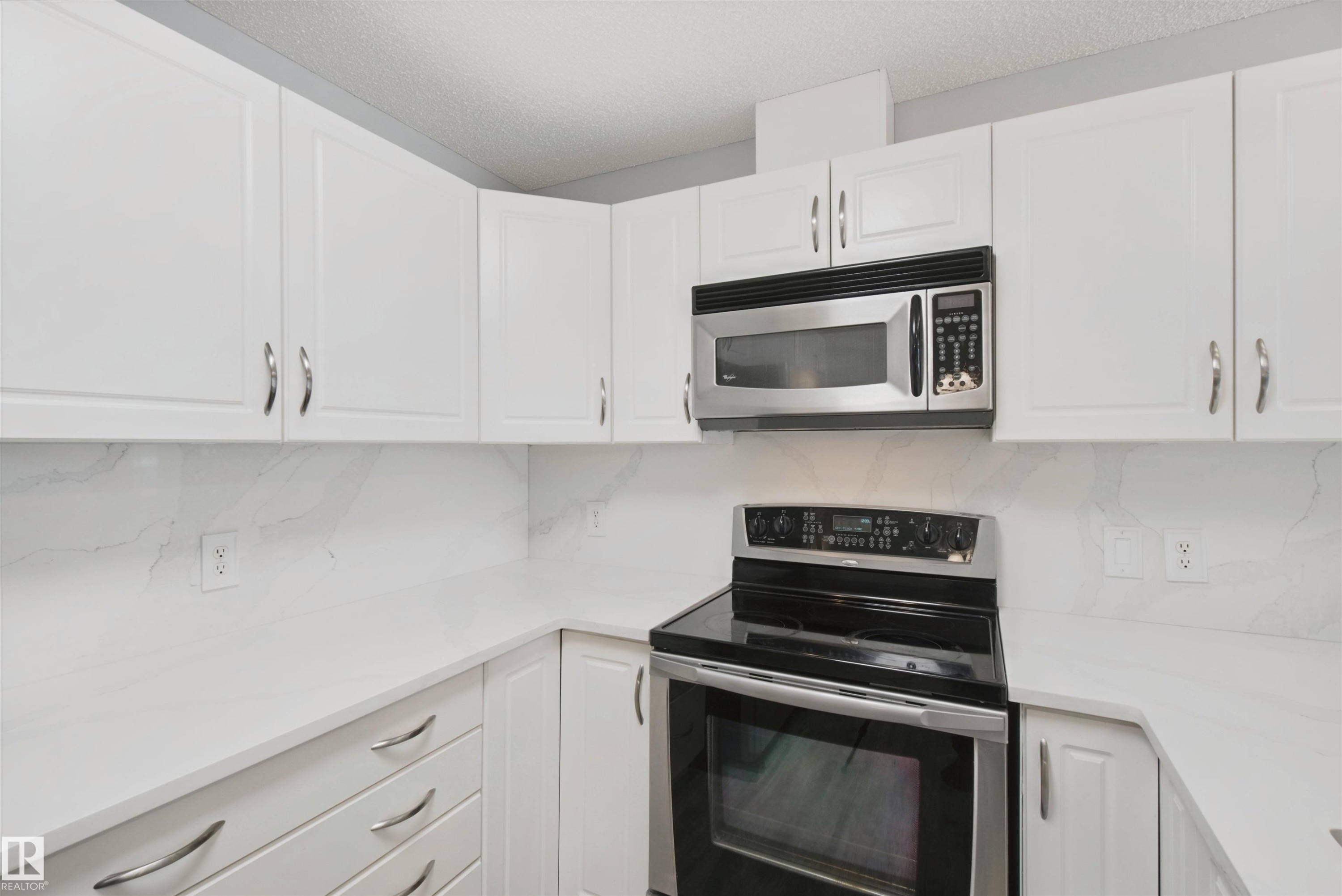 White cabinetry with chrome hardware - #208 16035 132 St Nw, Edmonton, AB