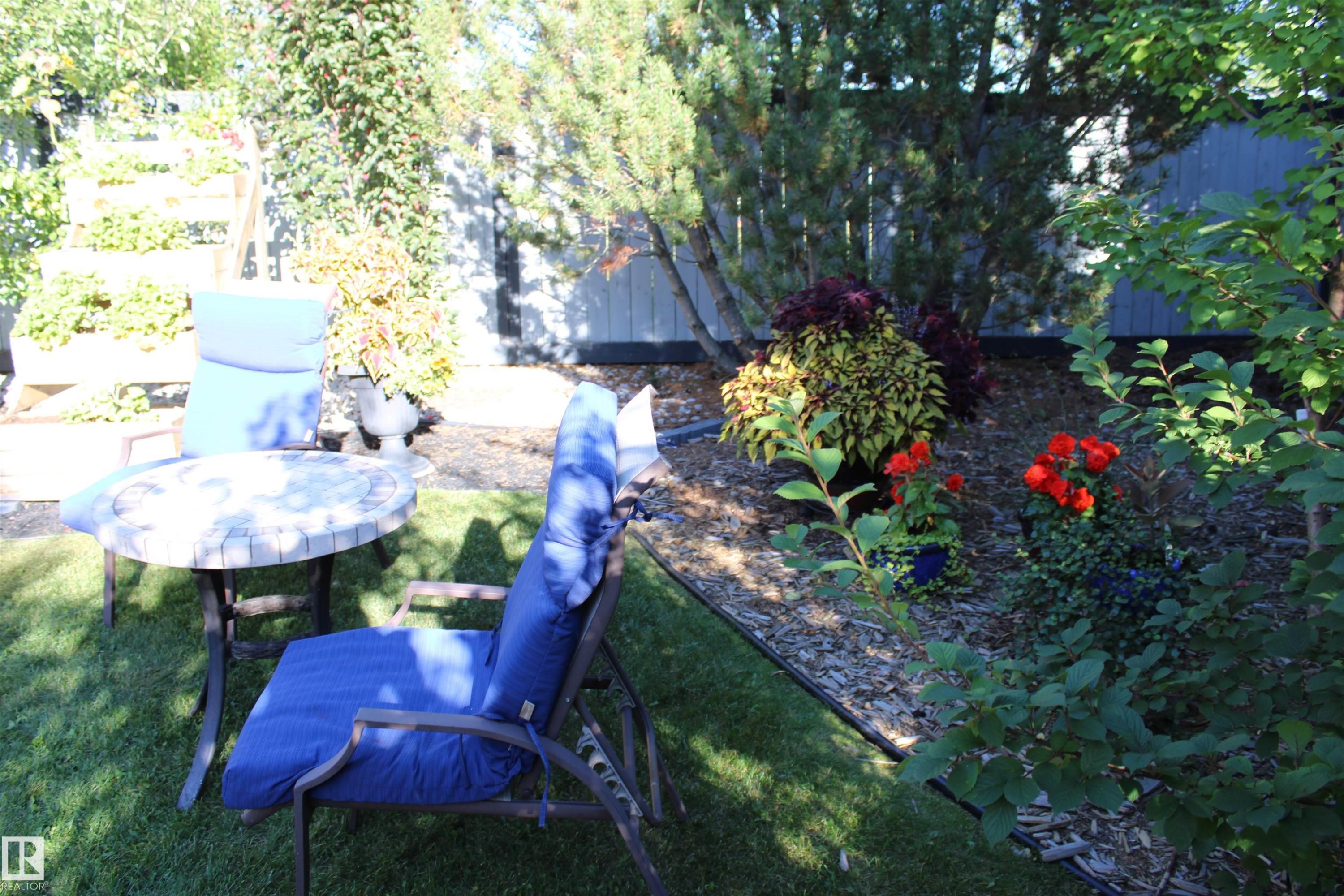 Manicured lawn area with an adjacent garden bed featuring various plantings - 3815 41 Street Nw, Edmonton, AB