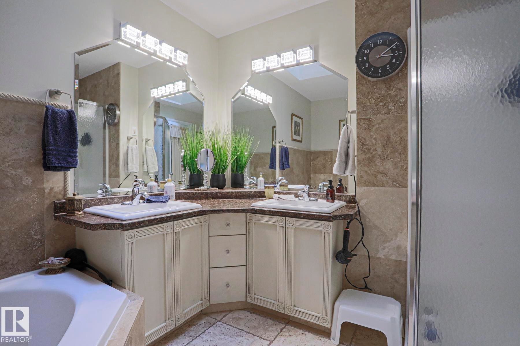 Dual vanity with integrated sinks, corner cabinetry, stone countertops, and tiled flooring - 3815 41 Street Nw, Edmonton, AB