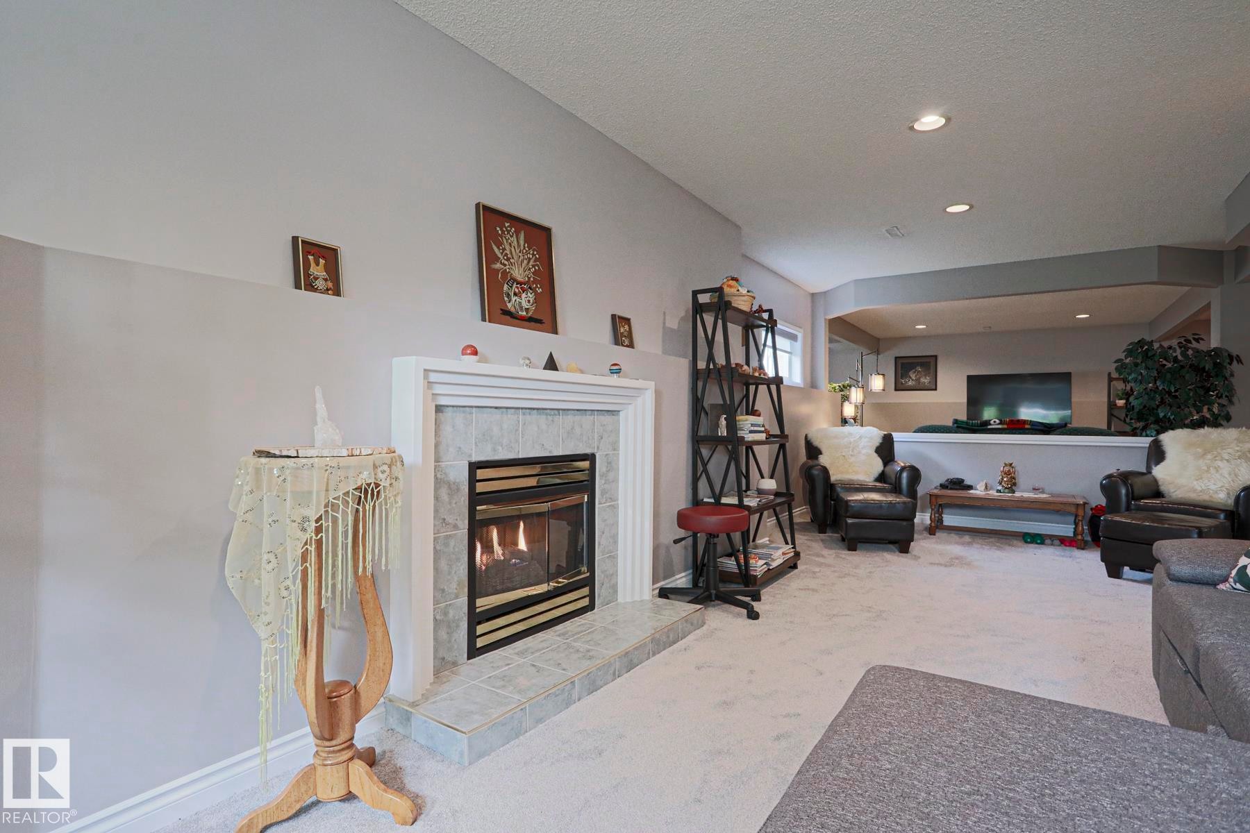 Fireplace with a tile surround and hearth, recessed lighting, and a partial wall separating spaces - 3815 41 Street Nw, Edmonton, AB