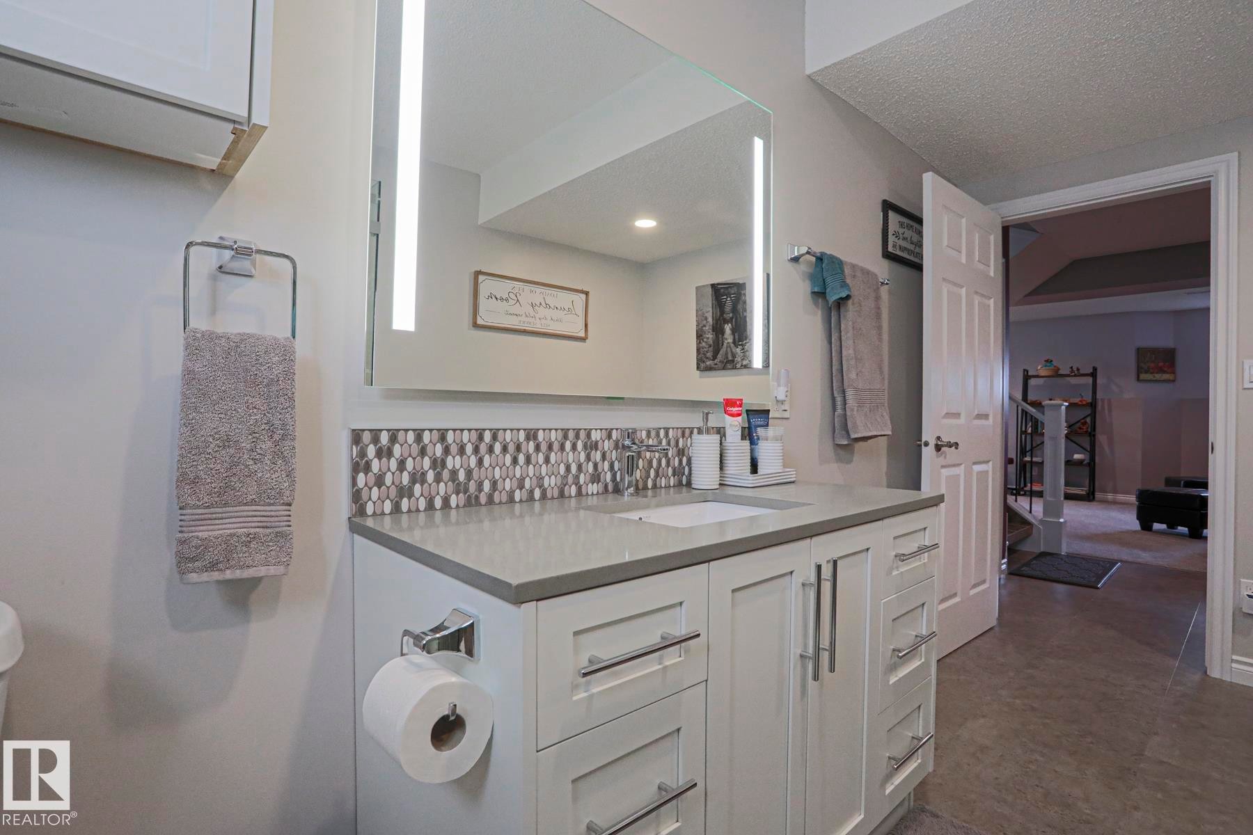 Vanity featuring a white undermount sink, light gray countertop, and mosaic tile backsplash - 3815 41 Street Nw, Edmonton, AB