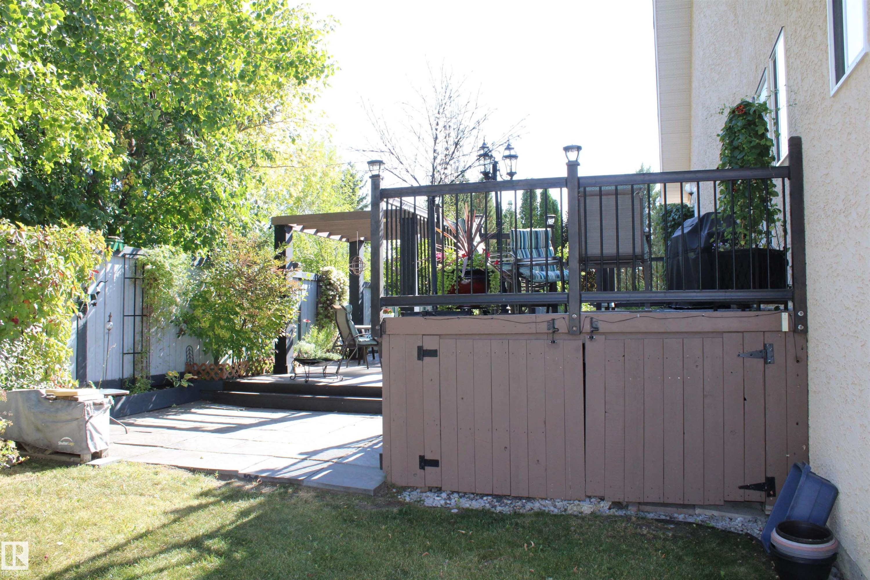 Expansive backyard featuring a manicured lawn, multi-level patio, and a separate deck with metal railings - 3815 41 Street Nw, Edmonton, AB