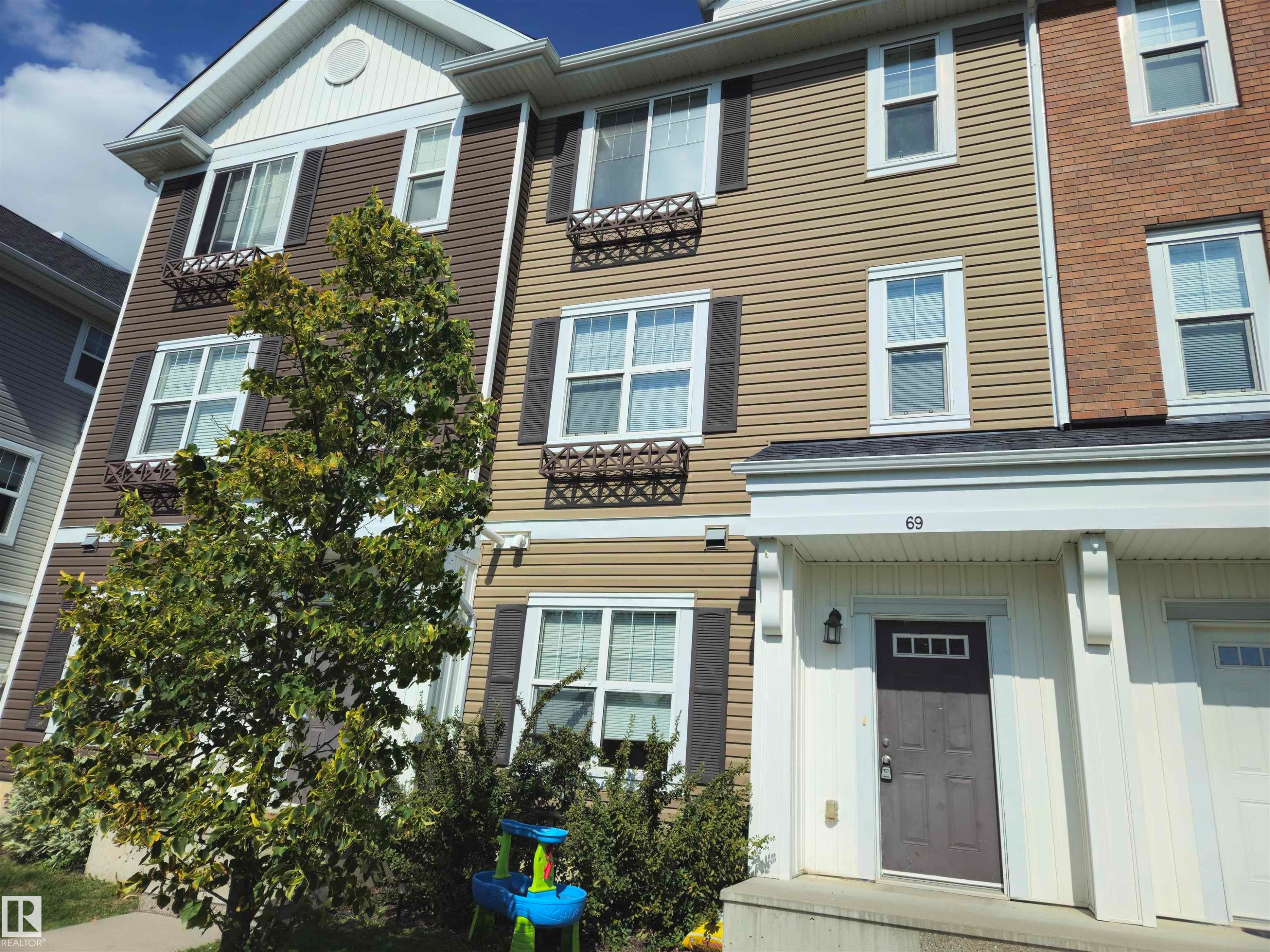 Multi-story property featuring horizontal siding, white window trim, dark window shutters, and decorative window boxes - #69 903 Crystallina Nera Wy Nw, Edmonton, AB