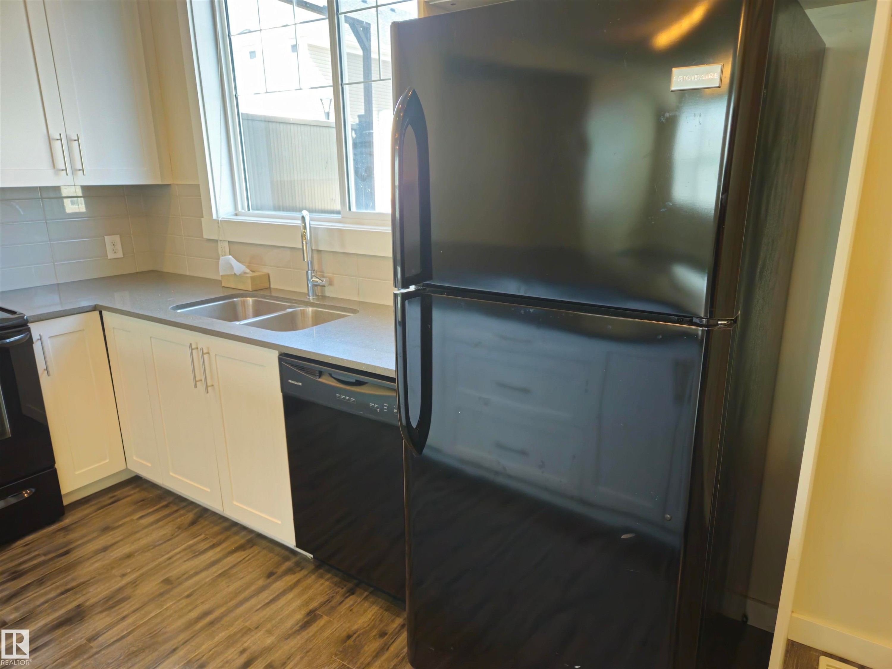 Kitchen featuring wood-finish flooring, white cabinetry, gray countertops, and a subway tile backsplash - #69 903 Crystallina Nera Wy Nw, Edmonton, AB