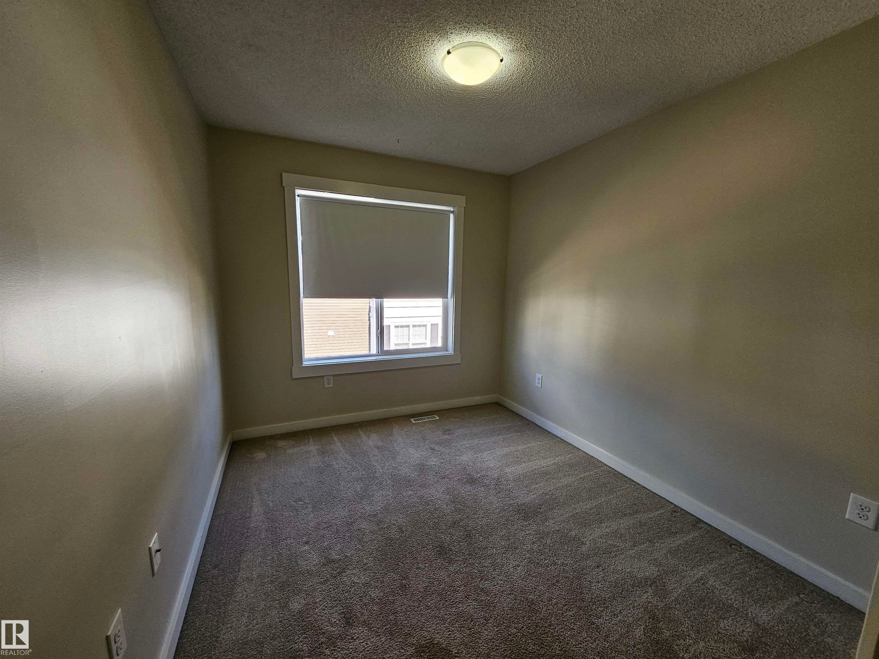 Neutral painted walls, gray carpet, window with white trim, roller shade, and overhead flush-mount lighting - #69 903 Crystallina Nera Wy Nw, Edmonton, AB