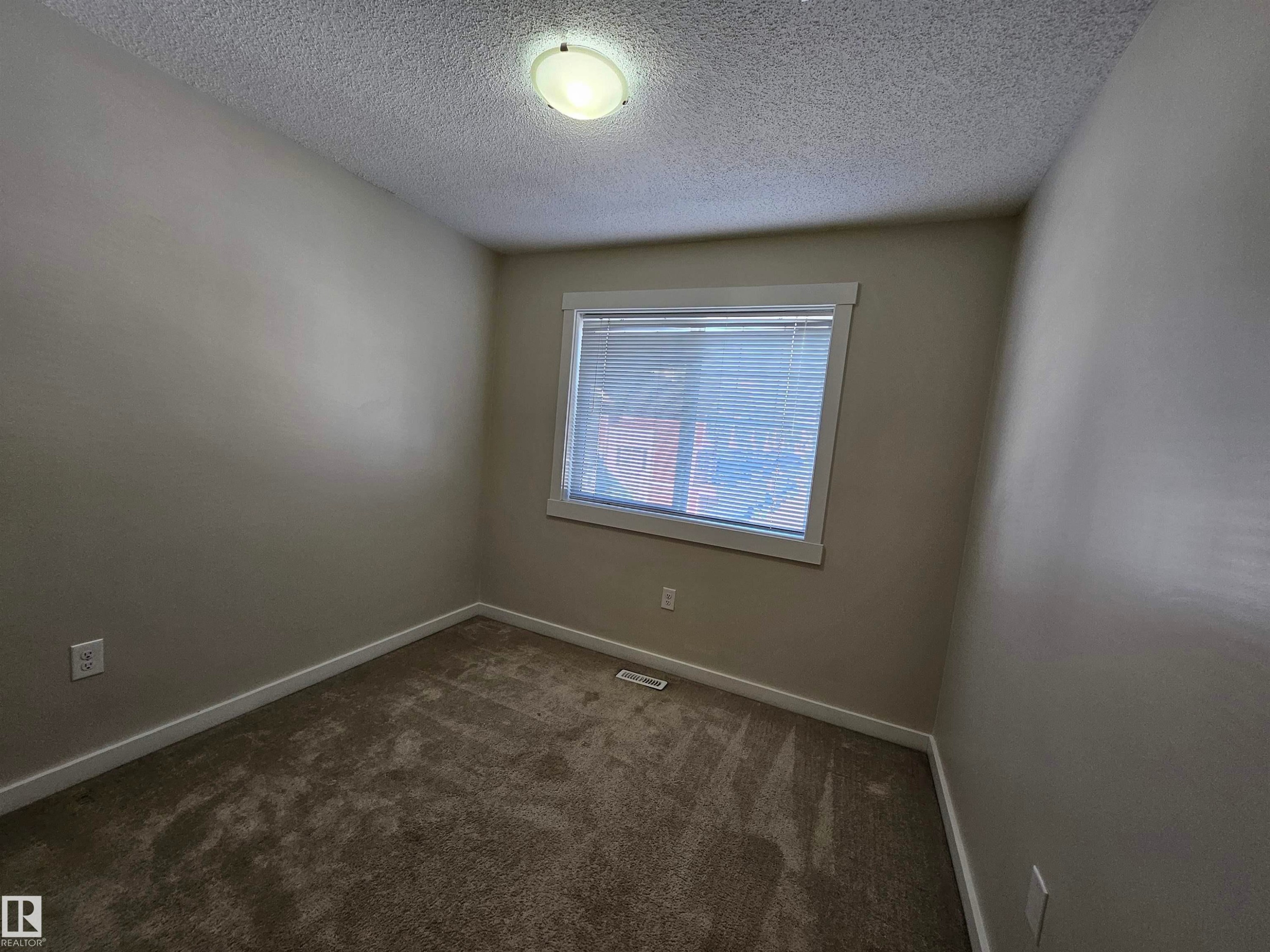 Carpeted room with a window featuring blinds, a ceiling-mounted light fixture, and neutral wall tones - #69 903 Crystallina Nera Wy Nw, Edmonton, AB