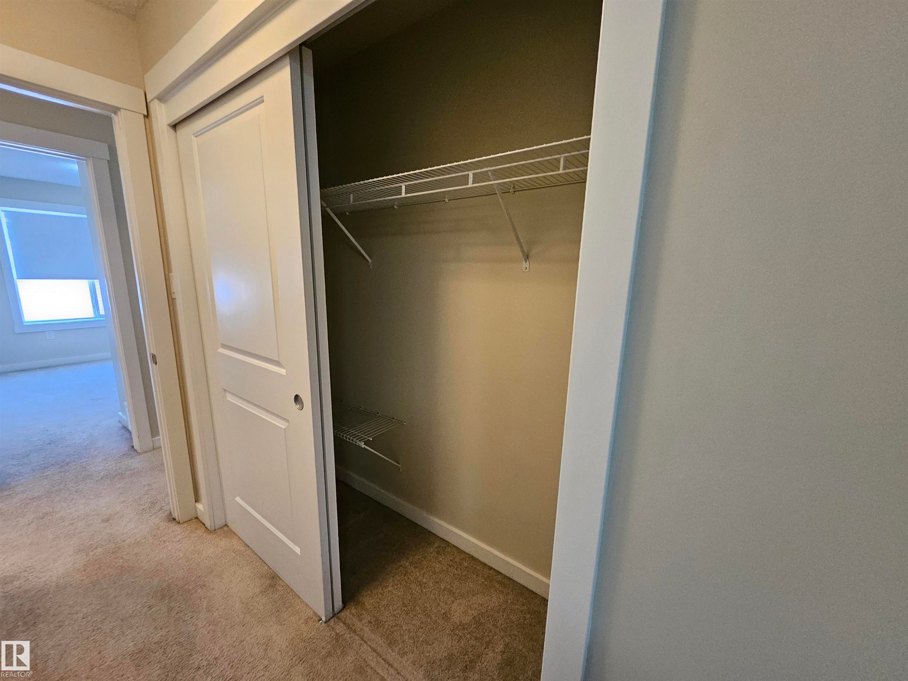 Carpeted flooring throughout, white sliding closet doors, and wire shelving system - #69 903 Crystallina Nera Wy Nw, Edmonton, AB