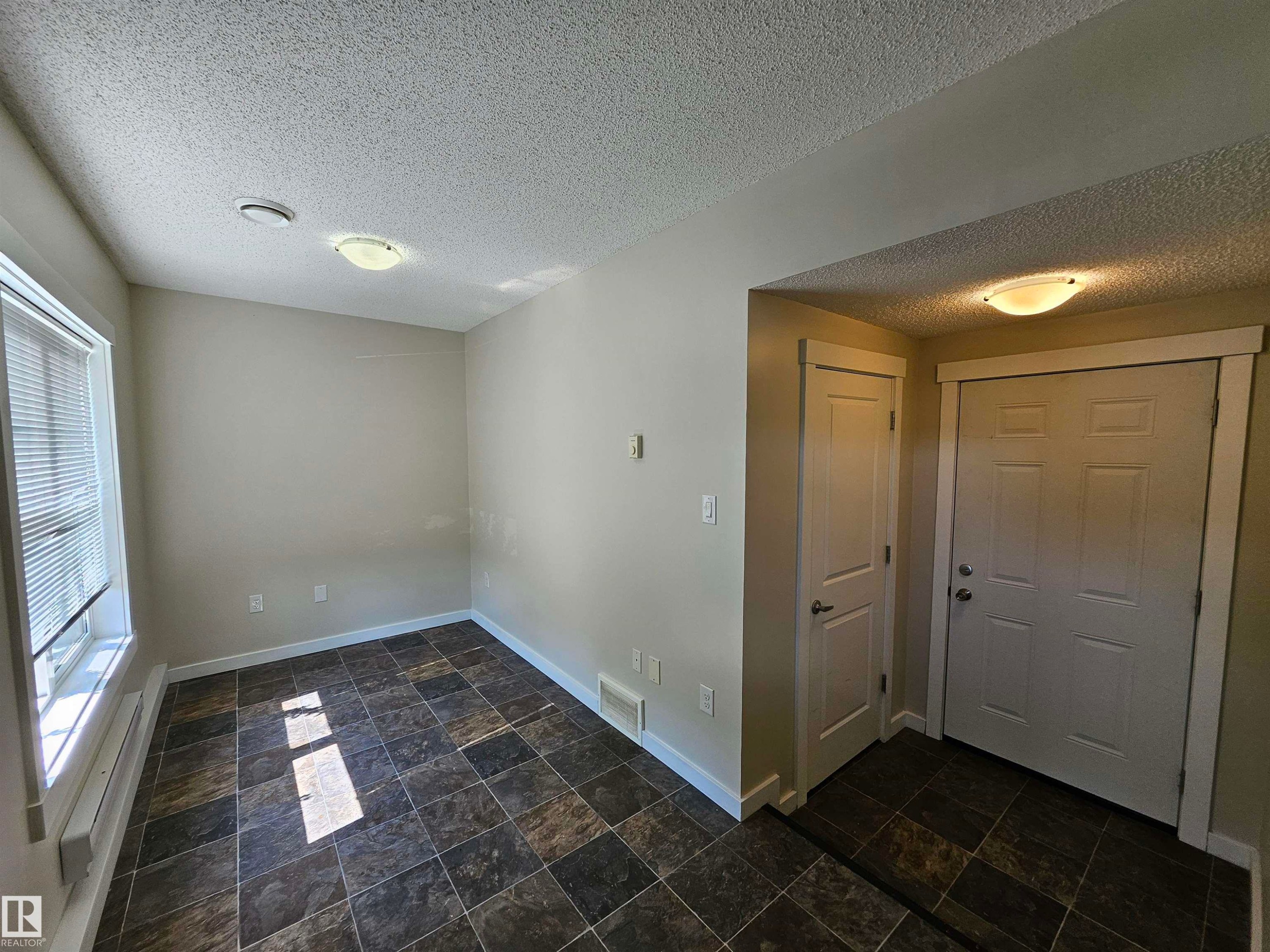 Entry area featuring a paneled door, flush-mount lighting, and textured ceiling - #69 903 Crystallina Nera Wy Nw, Edmonton, AB