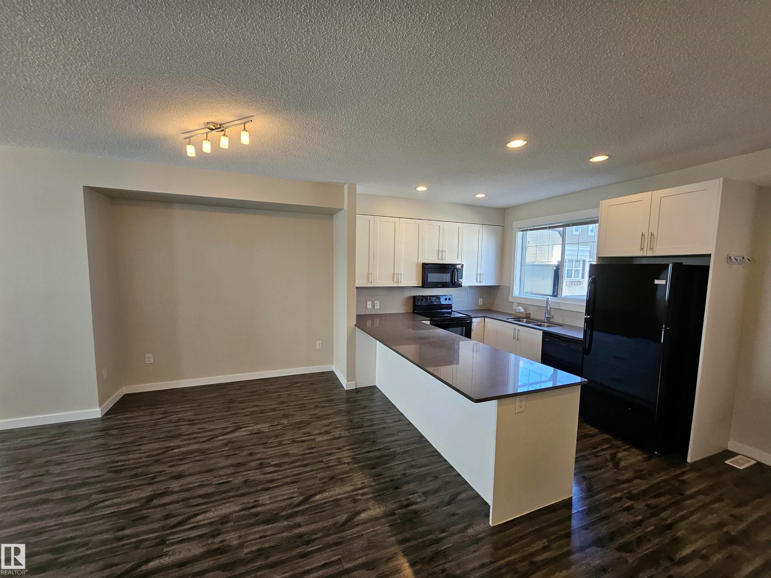 Open-concept living space with dark wood-finish flooring - #69 903 Crystallina Nera Wy Nw, Edmonton, AB