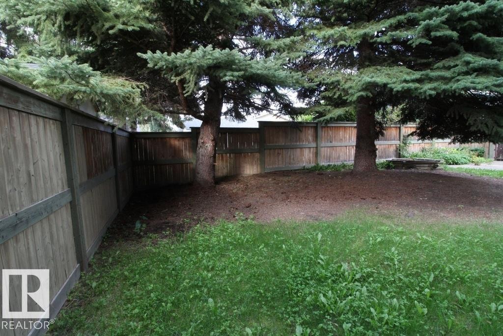 Expansive green space featuring established mature trees and a wood panel fence - 44 Arlington Drive, St. Albert, AB