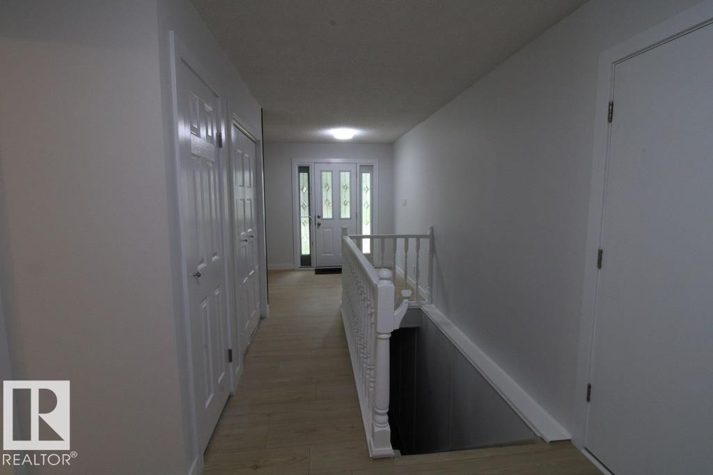 Entryway featuring wood-finish flooring, white paneled doors, and a decorative glass entry door - 44 Arlington Drive, St. Albert, AB