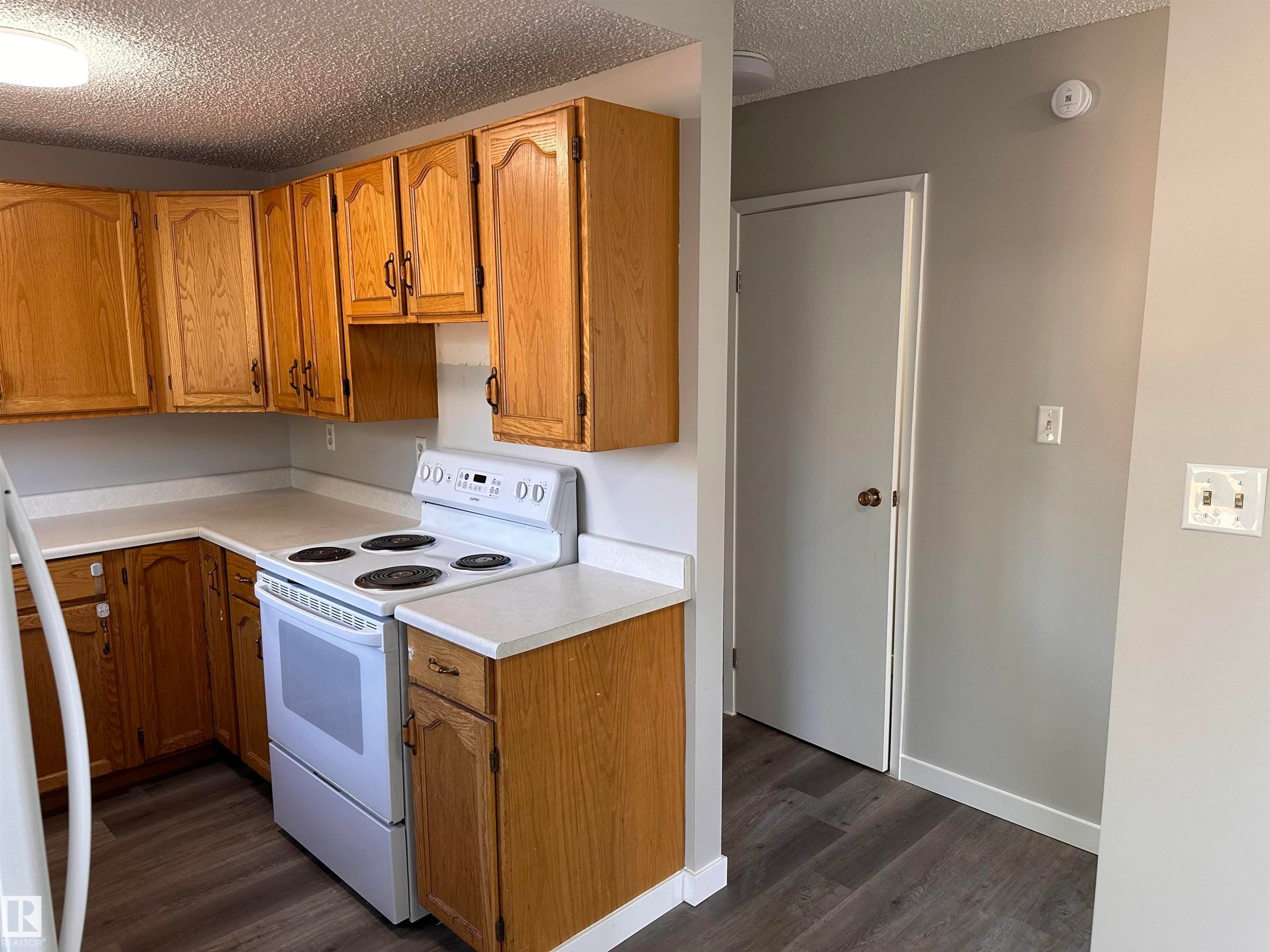 Kitchen featuring wood-finish cabinetry, white countertops, a white range, and wood-finish flooring - 9G Clareview Village Nw, Edmonton, AB