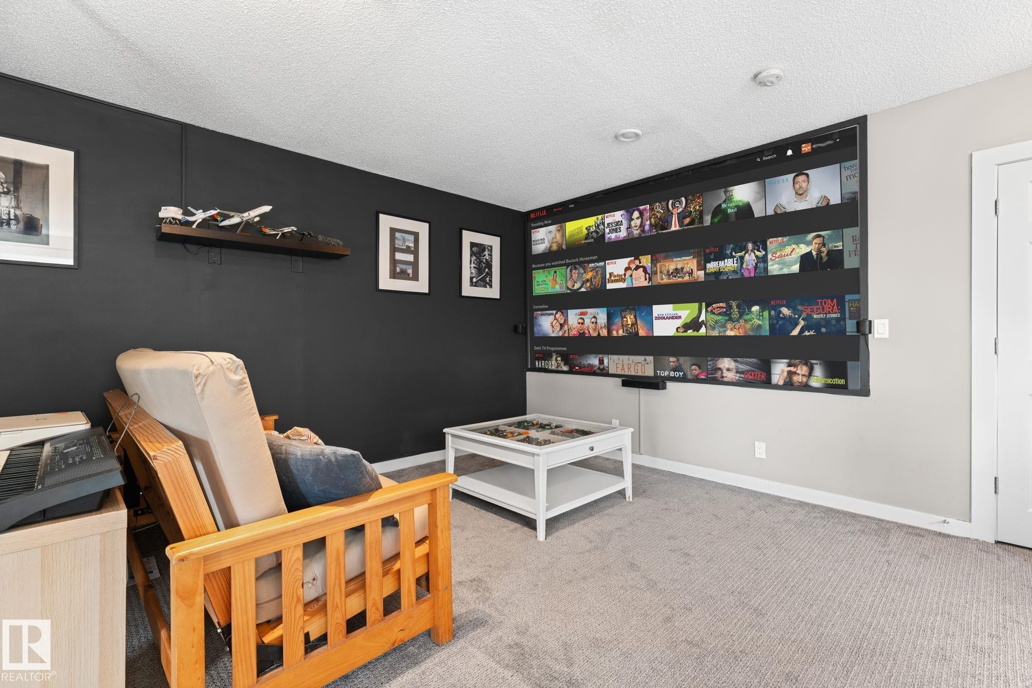 Built-in media screen wall, recessed ceiling lighting, light gray carpeting, and a white paneled door - #5 4900 62 St, Beaumont, AB