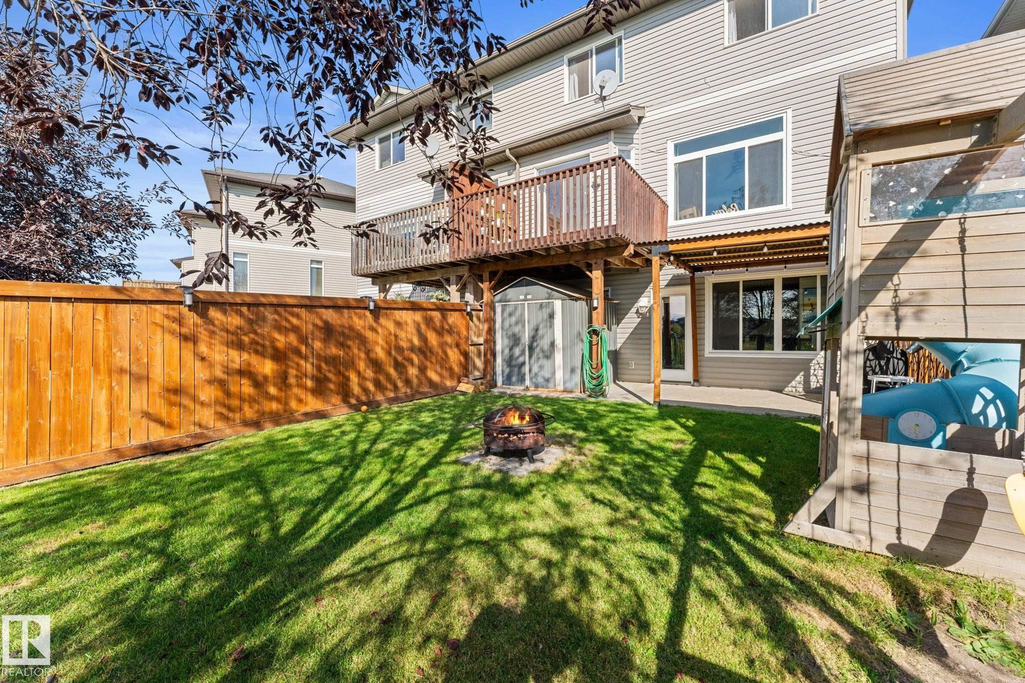 Expansive backyard featuring a manicured lawn, a wooden privacy fence, and a multi-level wood deck - #5 4900 62 St, Beaumont, AB