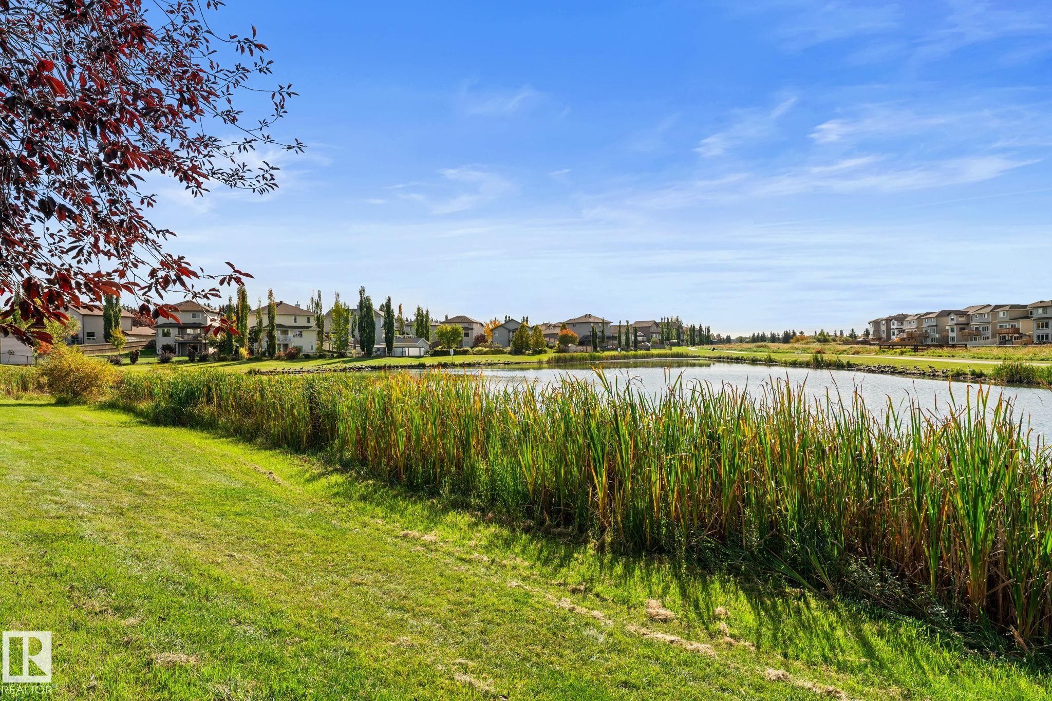 Expansive green space with mature plantings, bordering a tranquil water feature - #5 4900 62 St, Beaumont, AB