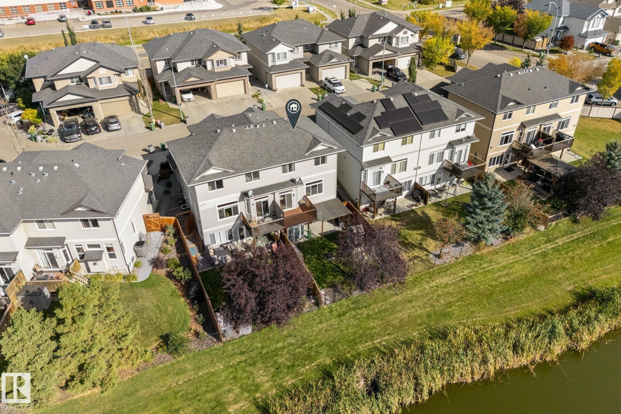 Rear exterior featuring multiple balconies, ground-level patios, and direct access to a natural waterway - #5 4900 62 St, Beaumont, AB