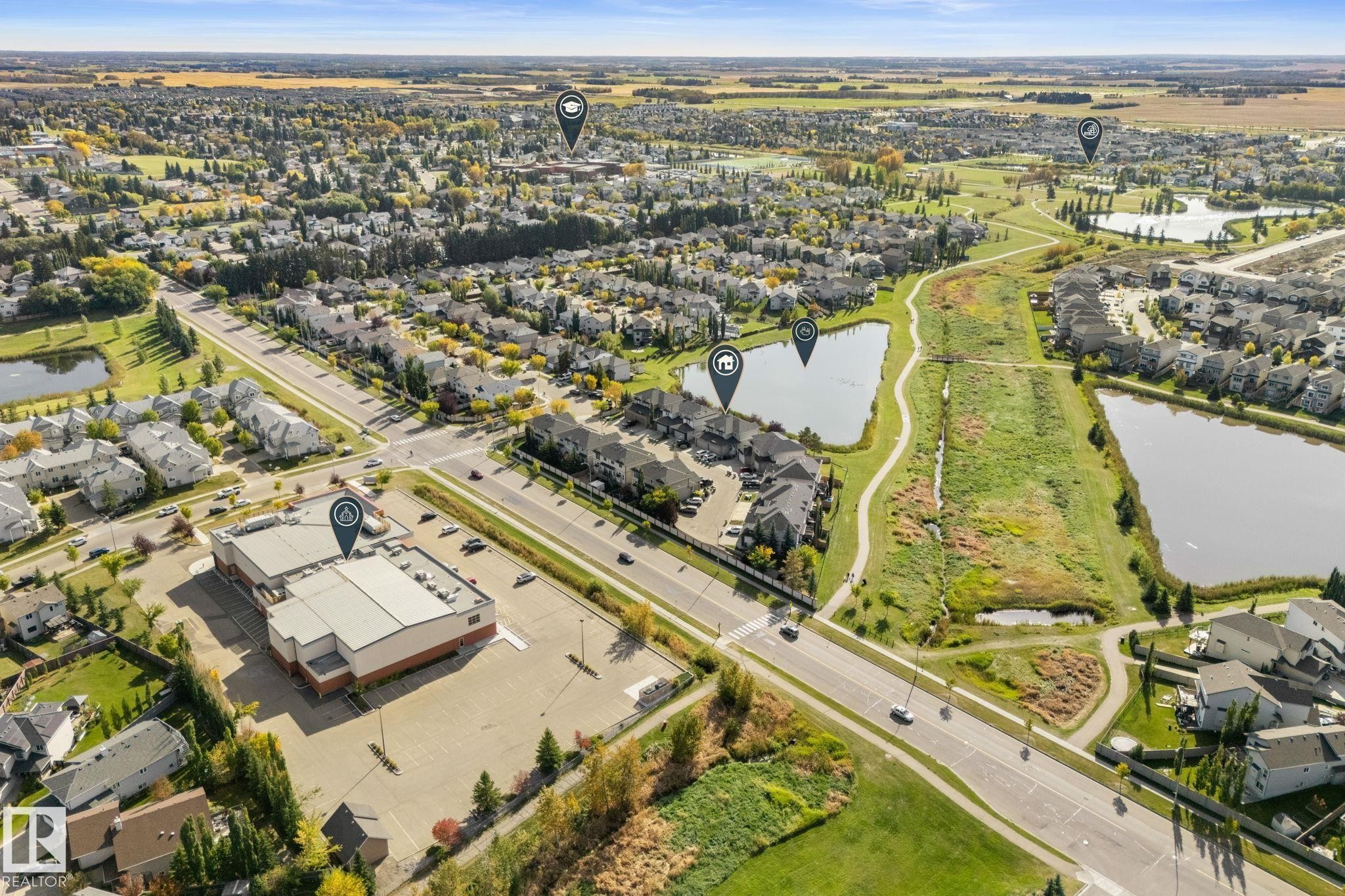 Expansive aerial capturing residential properties, paved roads, and multiple bodies of water - #5 4900 62 St, Beaumont, AB