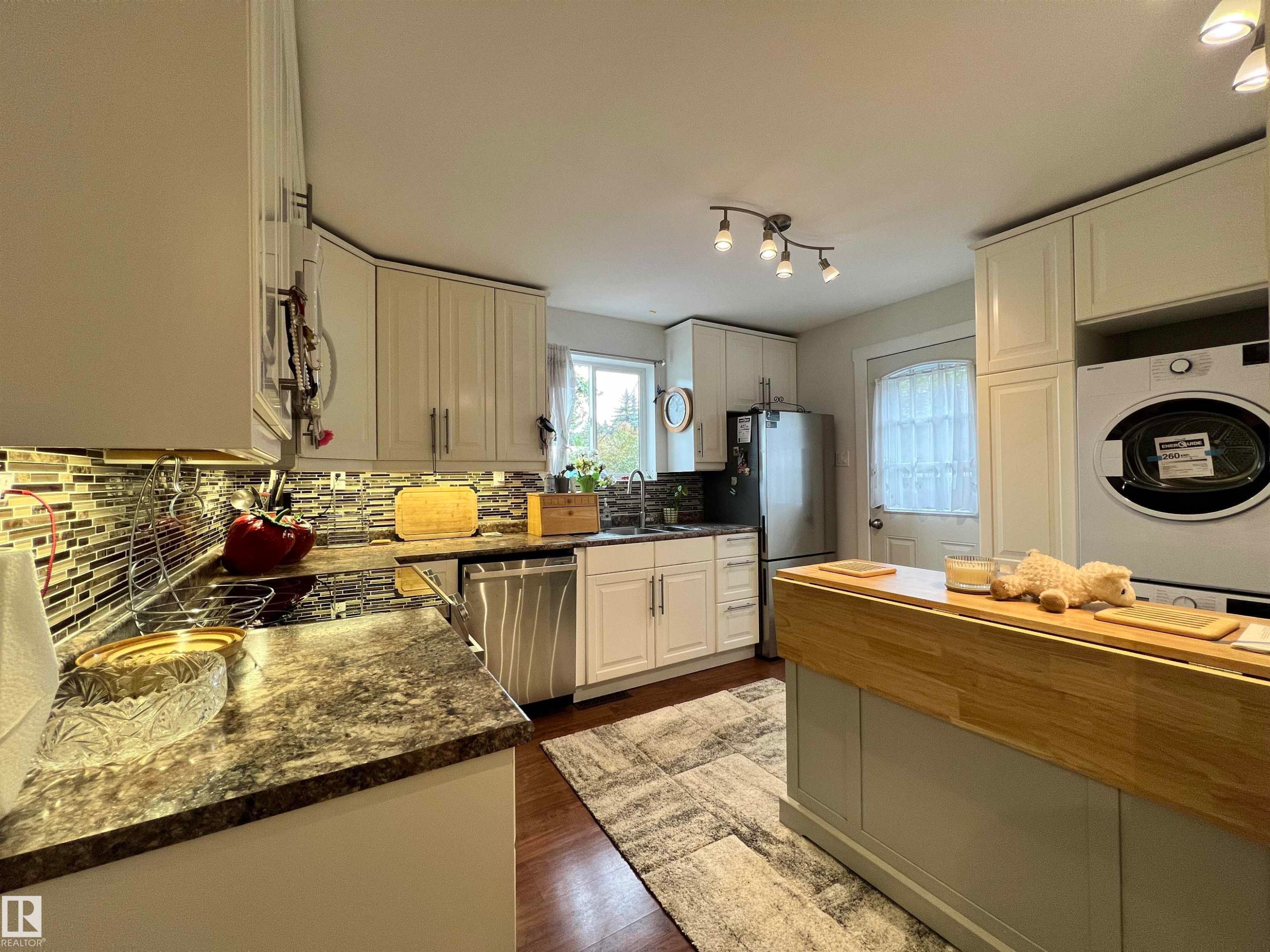 Kitchen featuring white cabinetry, a mosaic tile backsplash, a built-in cooktop, and a built-in stainless steel dishwasher - 11908 131 Street Nw, Edmonton, AB