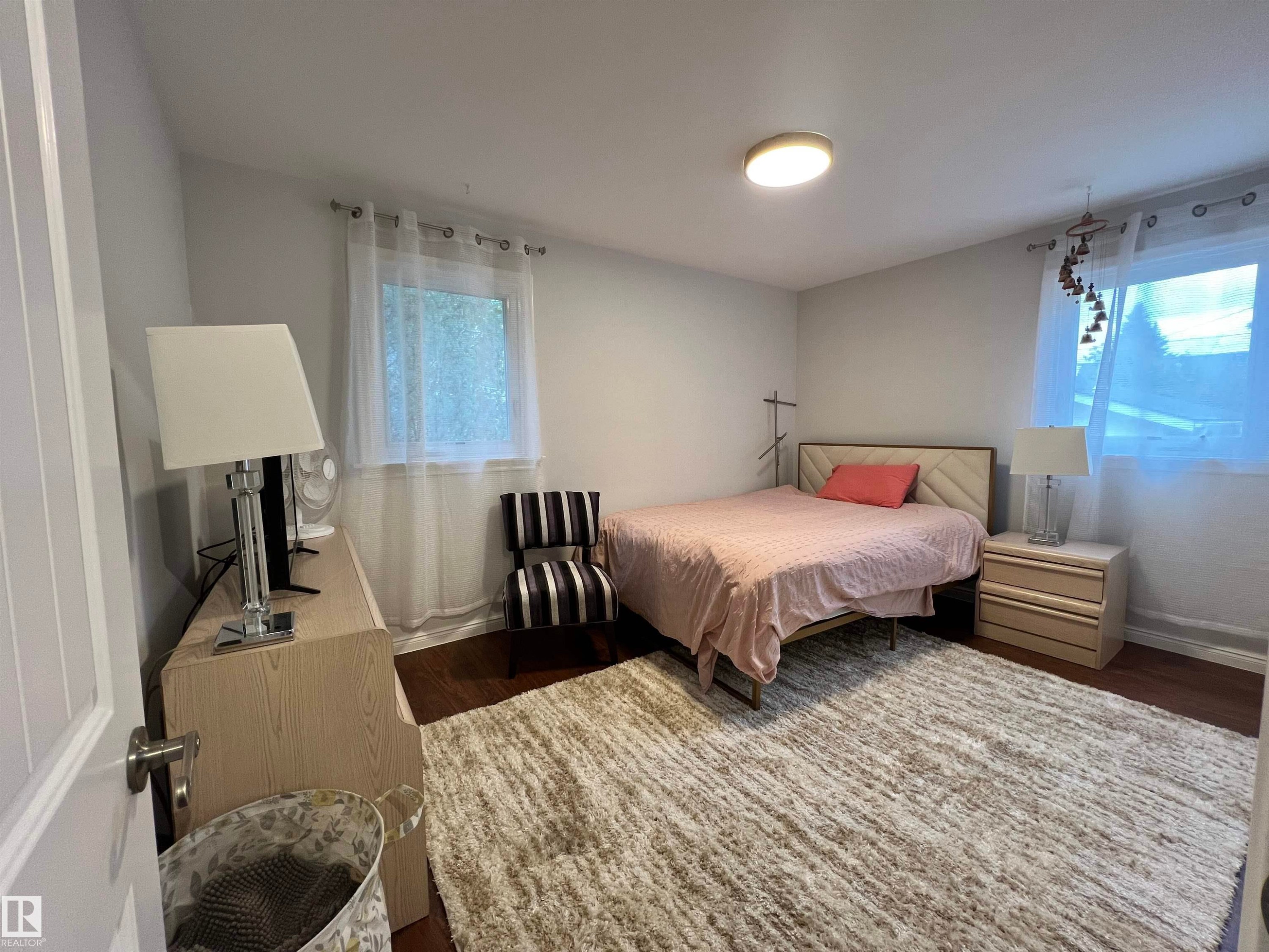 Recessed lighting fixture, two windows with sheers, wood-finish flooring, built-in dresser, and wall-mounted light fixture - 11908 131 Street Nw, Edmonton, AB