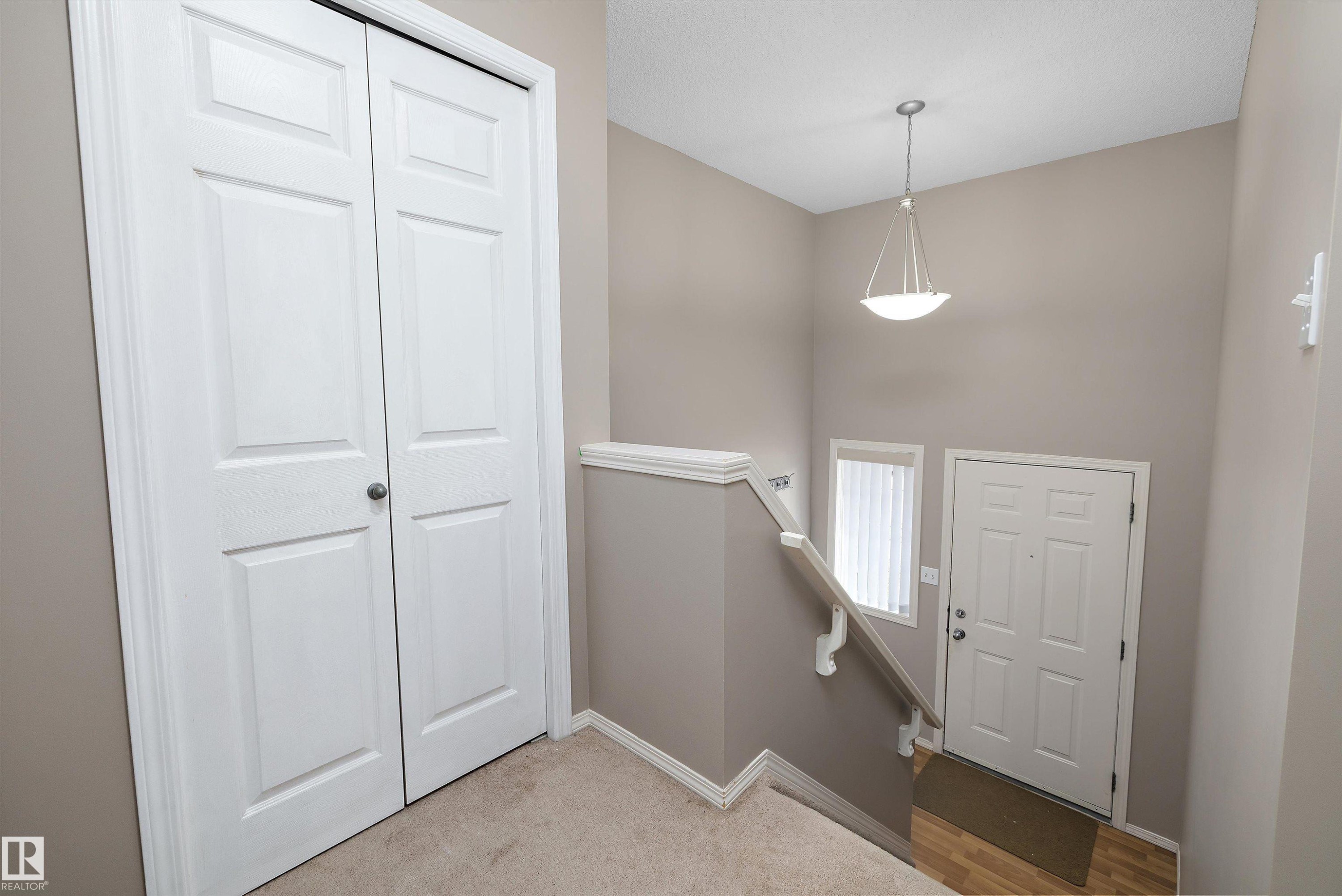 Entryway featuring a pendant light fixture, white paneled door, and wood-finish flooring - 3114 32 Avenue Nw, Edmonton, AB