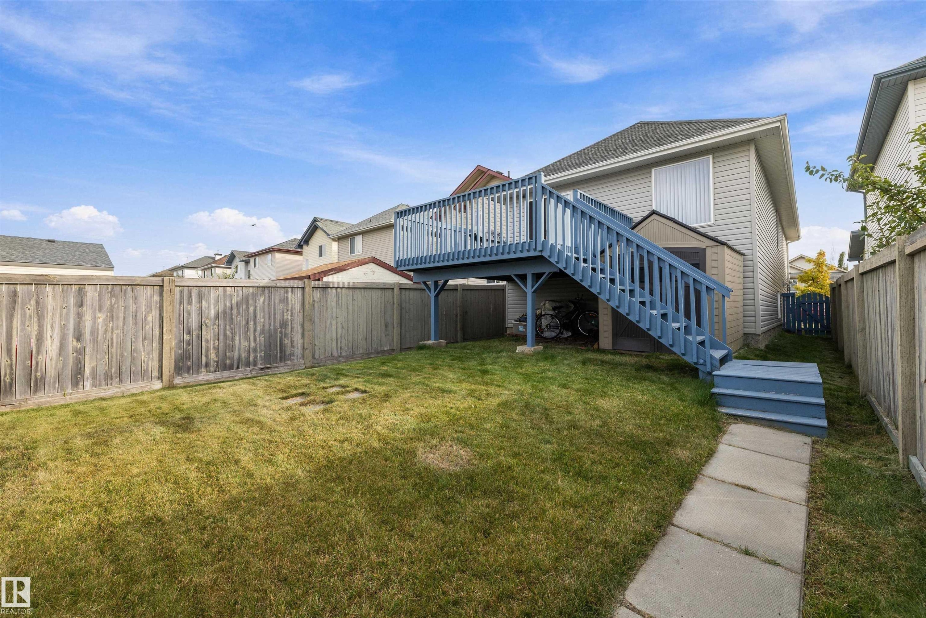Expansive lawn area with a multi-level deck featuring a blue painted railing and steps - 3114 32 Avenue Nw, Edmonton, AB