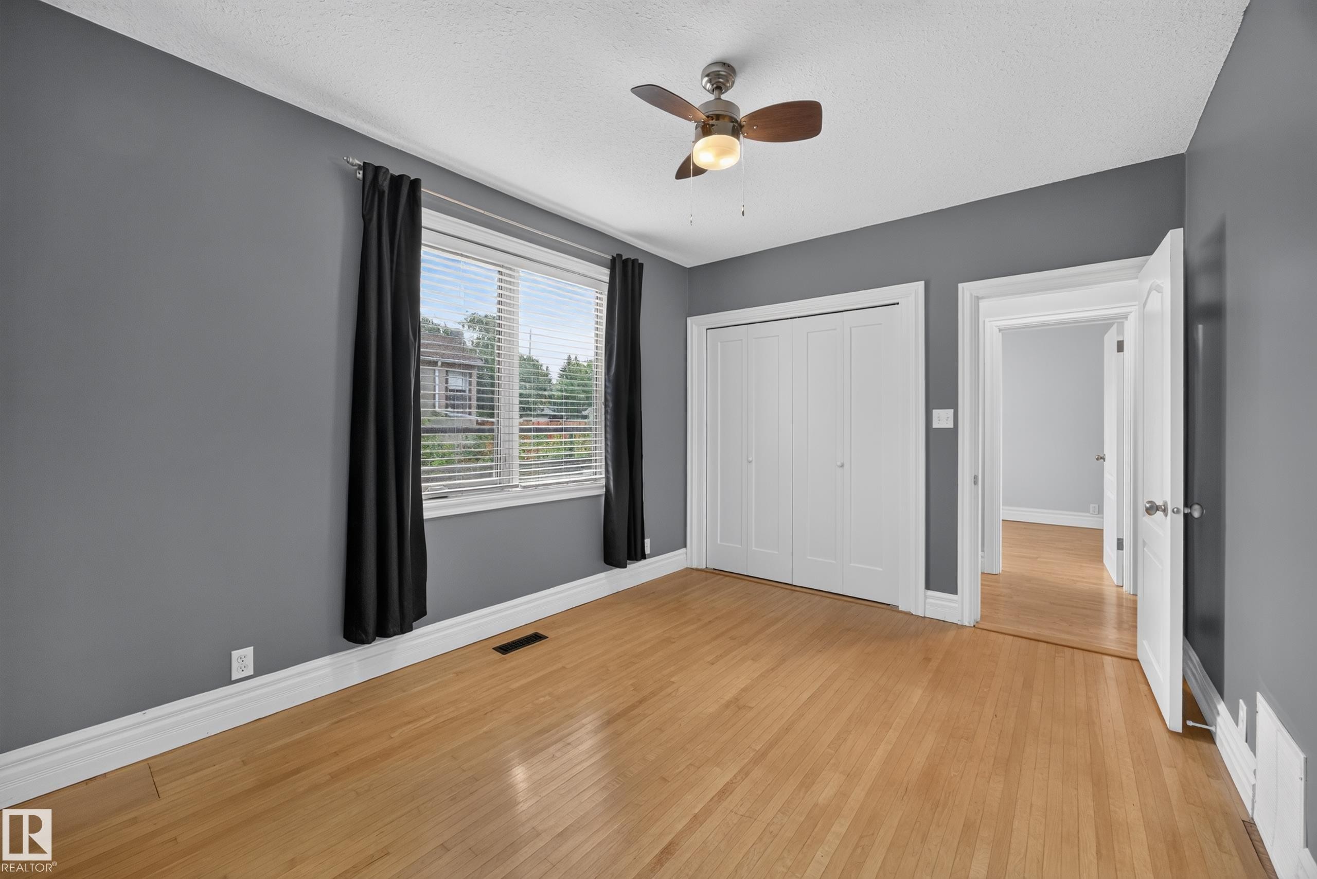 Hardwood flooring, crisp white trim, a ceiling fan, and bi-fold closet doors - 9615 75 Avenue Nw, Edmonton, AB