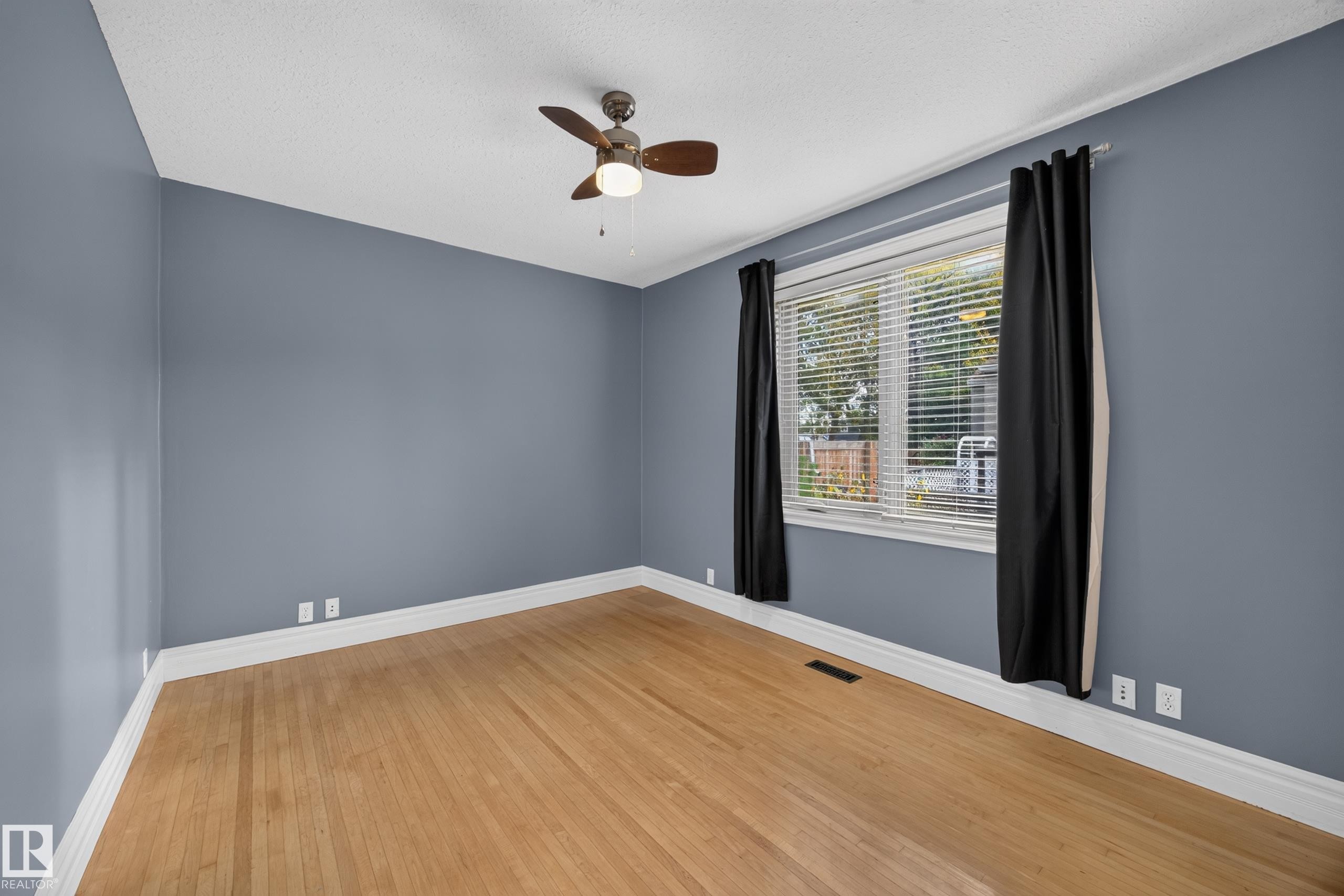 Wood-finish flooring with white trim, a ceiling fan, and a window with blinds - 9615 75 Avenue Nw, Edmonton, AB
