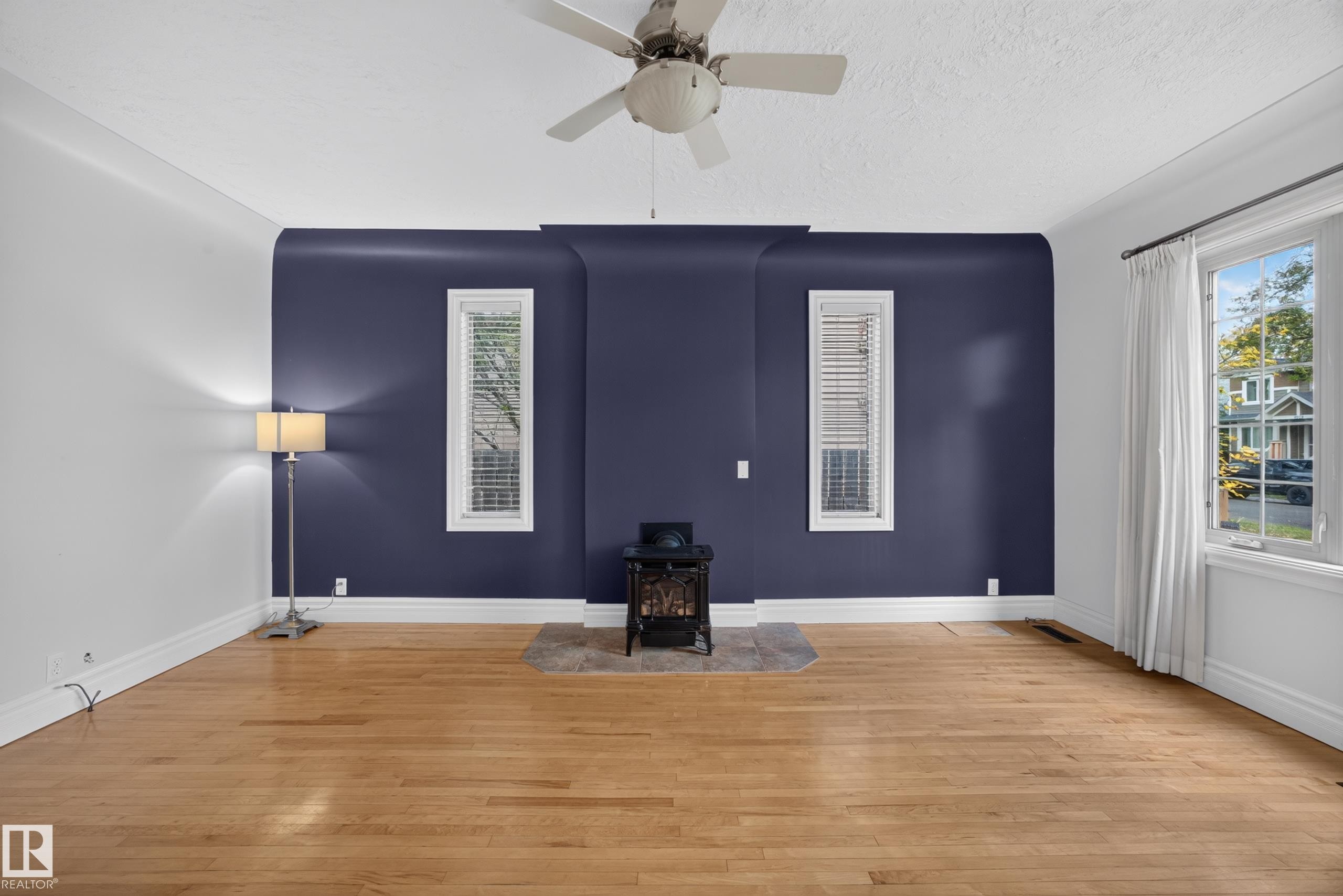 Hardwood flooring, painted accent wall, ceiling fan, and white trim - 9615 75 Avenue Nw, Edmonton, AB