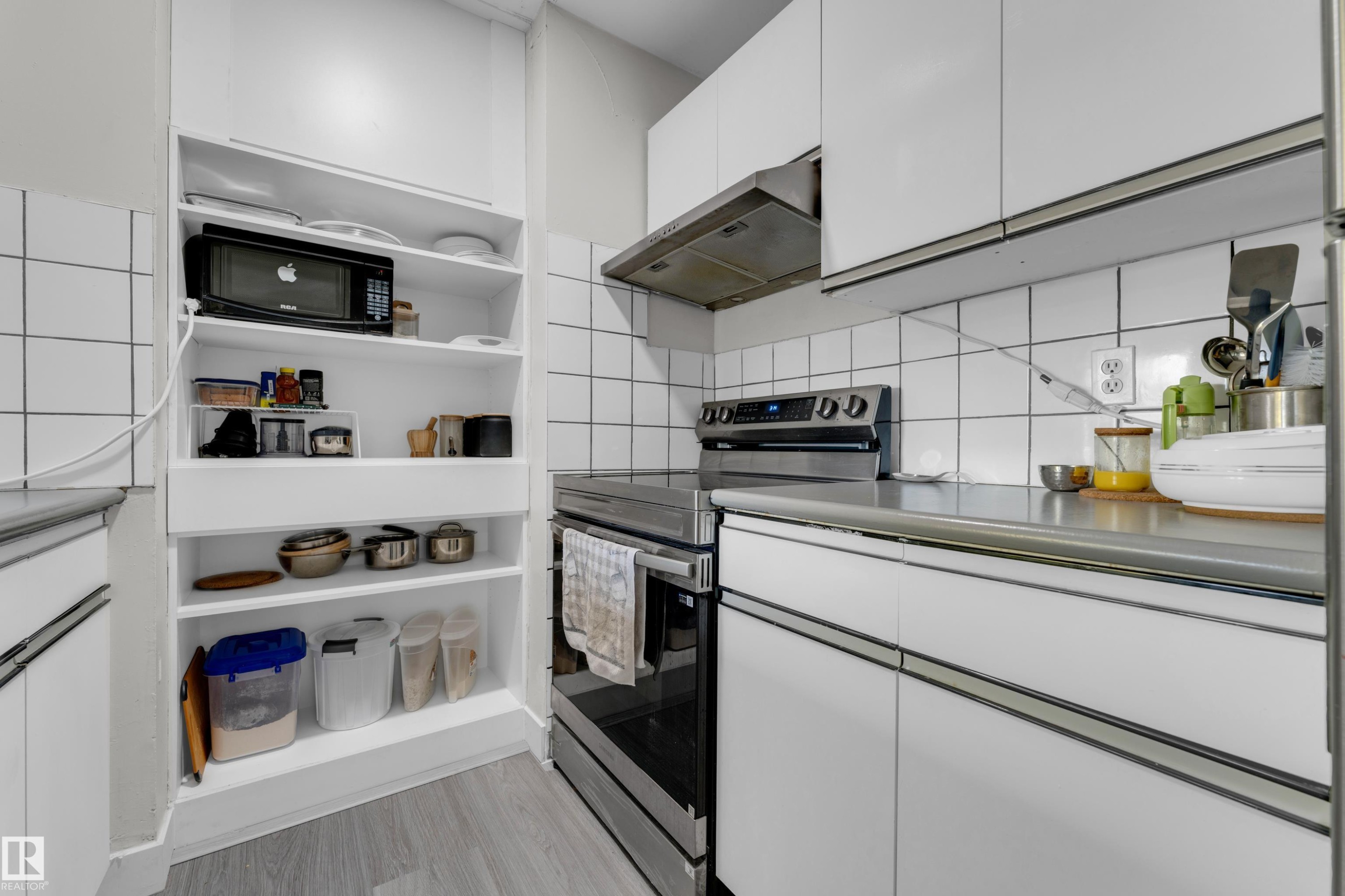 Kitchen featuring white shaker-style cabinetry, a stainless steel range, a stainless steel range hood, and white square tile backsplash - #113 2508 50 St Nw, Edmonton, AB