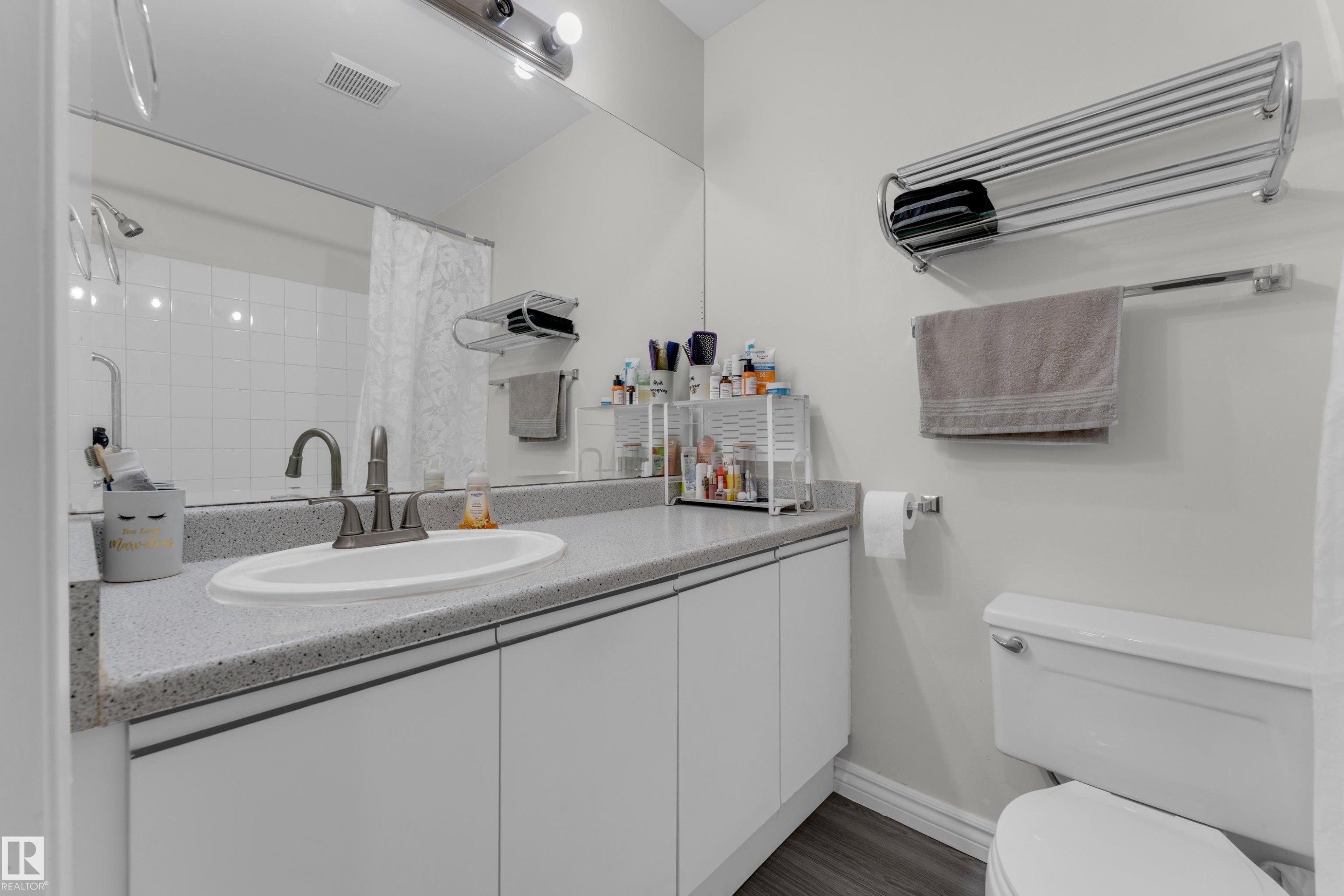 Bathroom featuring a vanity with an integrated sink, a speckled countertop, and white cabinetry - #113 2508 50 St Nw, Edmonton, AB