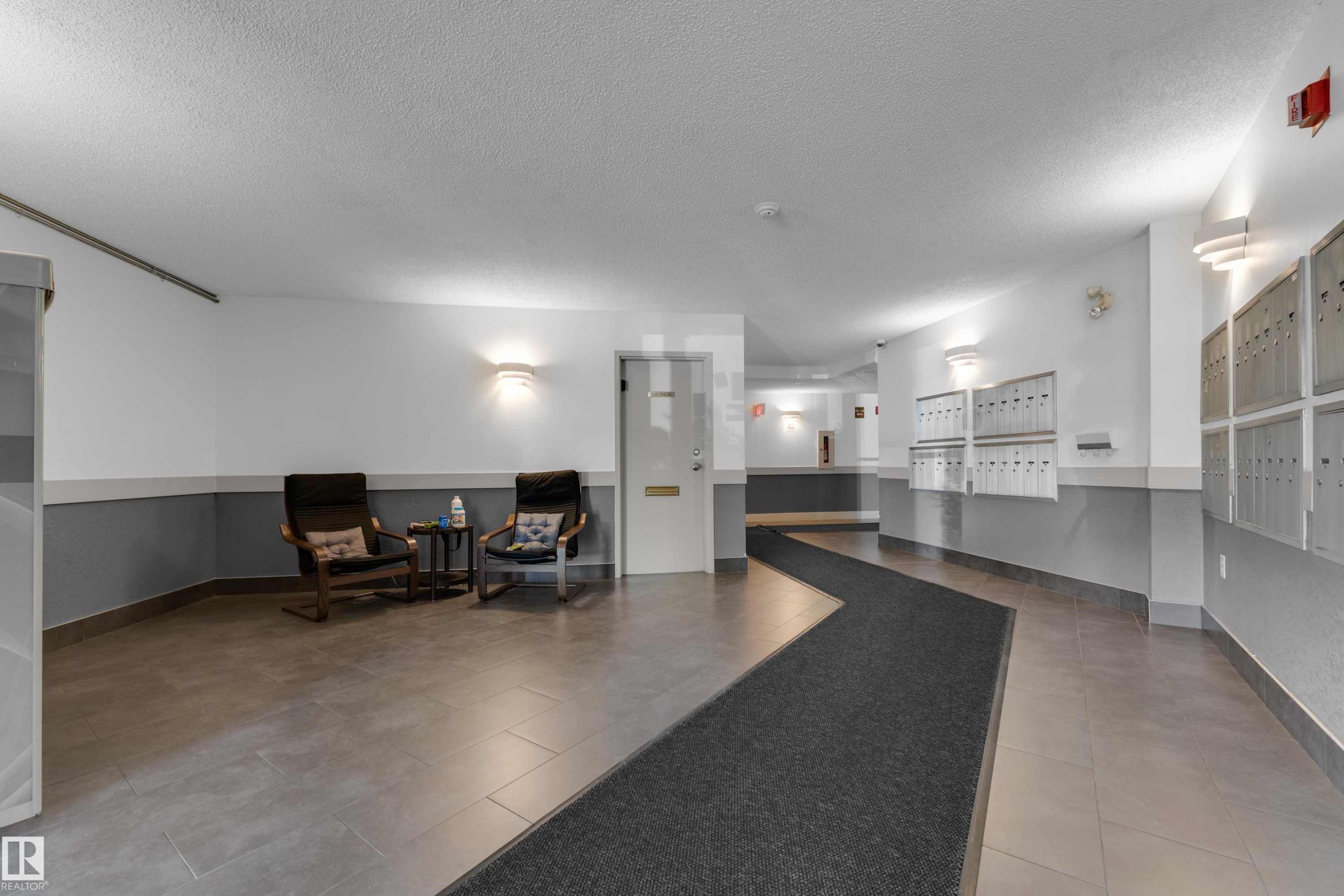 Tiled flooring throughout with a dark runner, two-tone wall treatment, and wall-mounted sconces - #113 2508 50 St Nw, Edmonton, AB