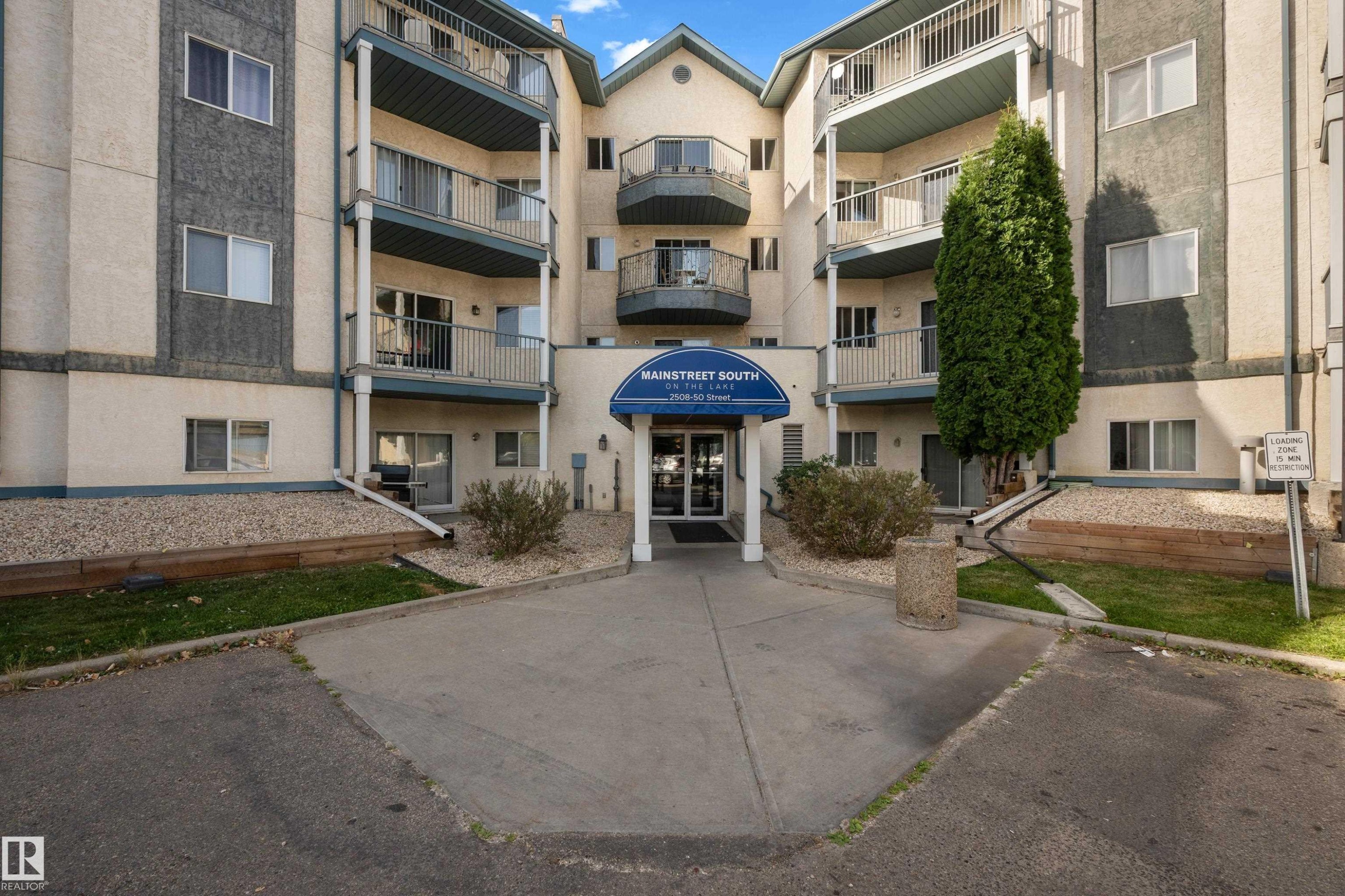 Multi-story building exterior with individual balconies, covered main entrance, and mature landscaping - #113 2508 50 St Nw, Edmonton, AB