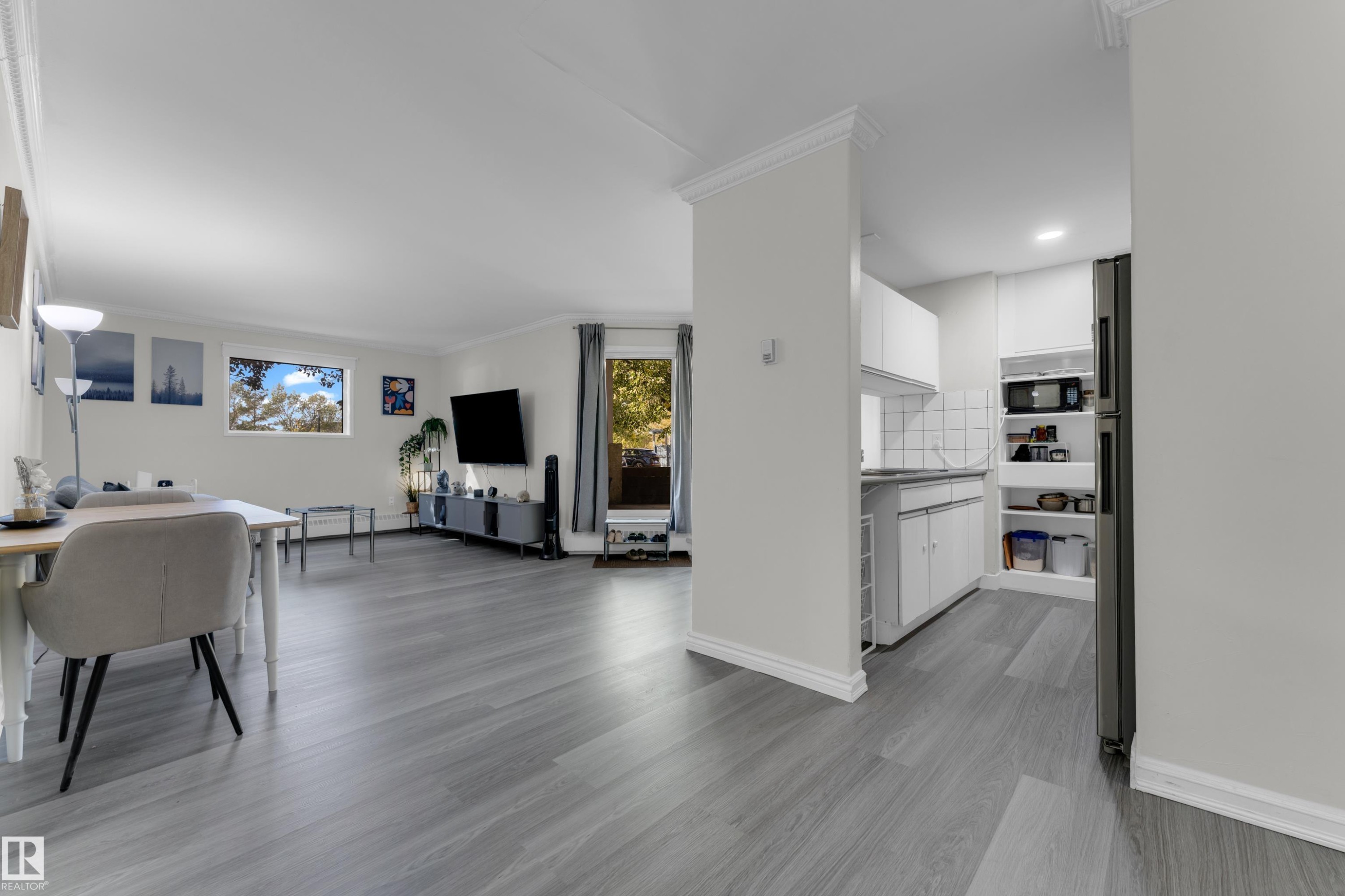 Open-concept living space with light wood-finish flooring, crown molding, and recessed lighting - #113 2508 50 St Nw, Edmonton, AB