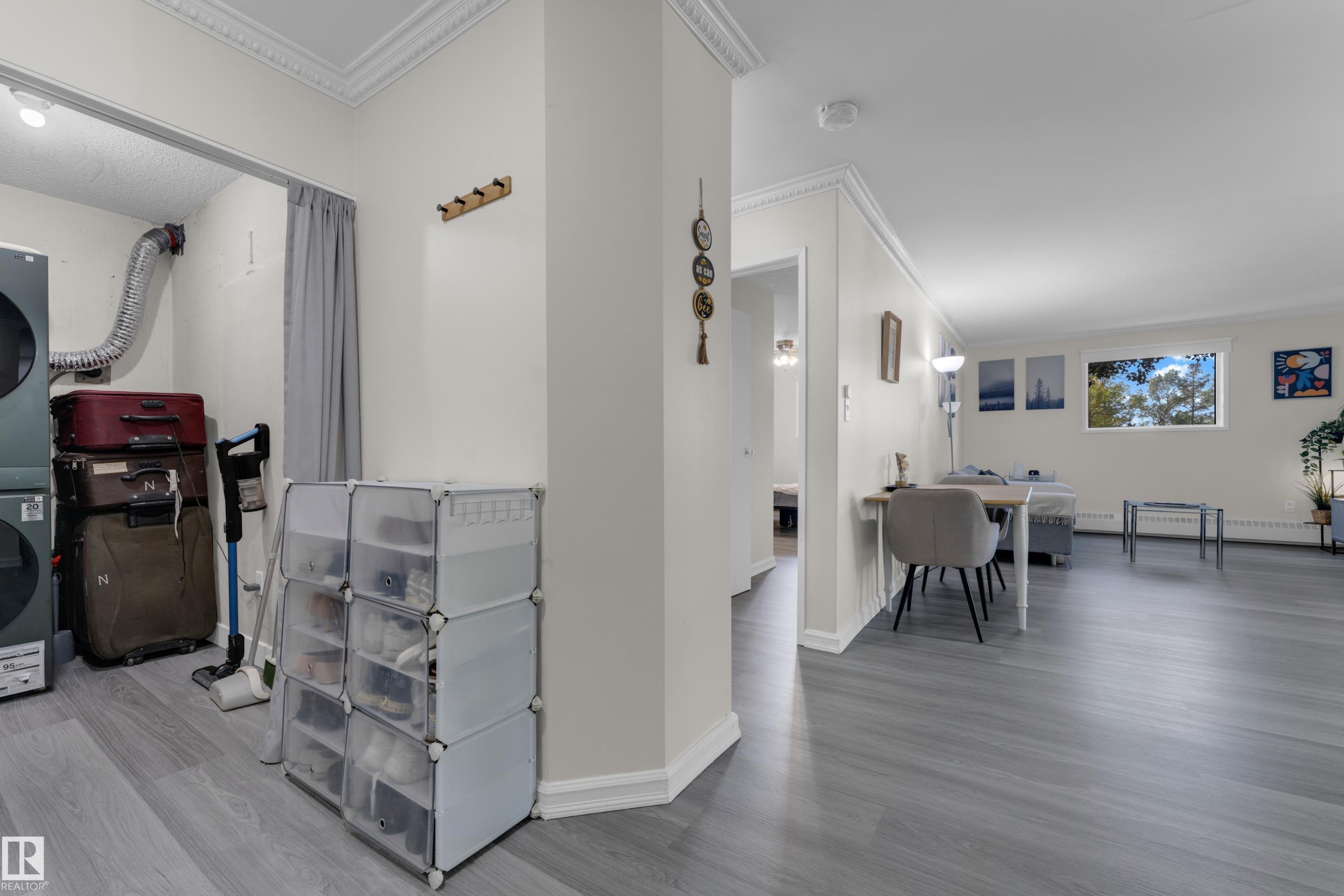 White walls with crown molding, light wood-finish flooring, and a window with exterior scenery - #113 2508 50 St Nw, Edmonton, AB