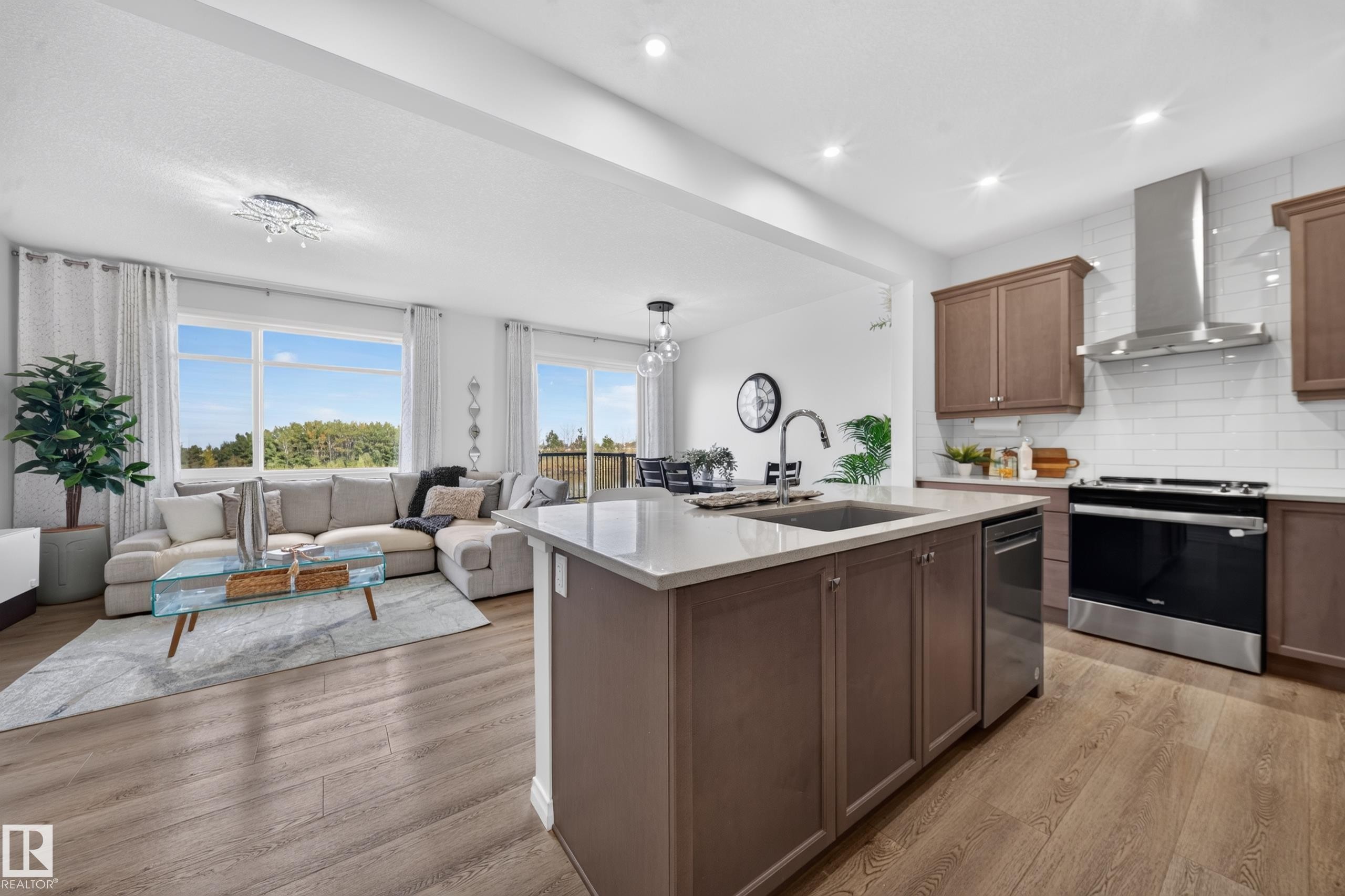 Open-concept living space featuring wood-finish flooring, recessed lighting, and large windows - 4104 3 Avenue Sw, Edmonton, AB