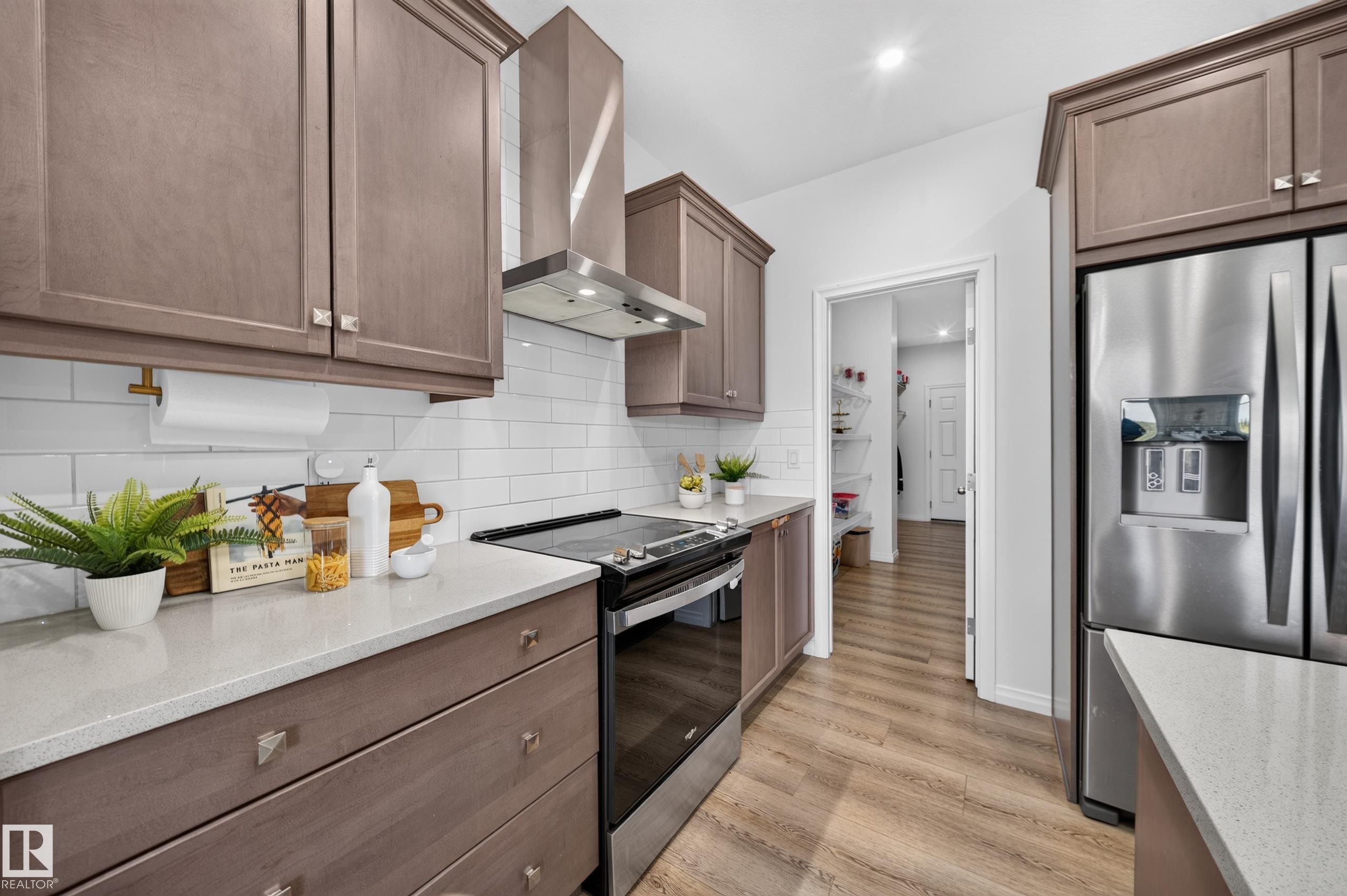 Stainless steel appliances, wood-finish flooring, white subway tile backsplash, light-toned cabinetry, and light-toned countertops - 4104 3 Avenue Sw, Edmonton, AB