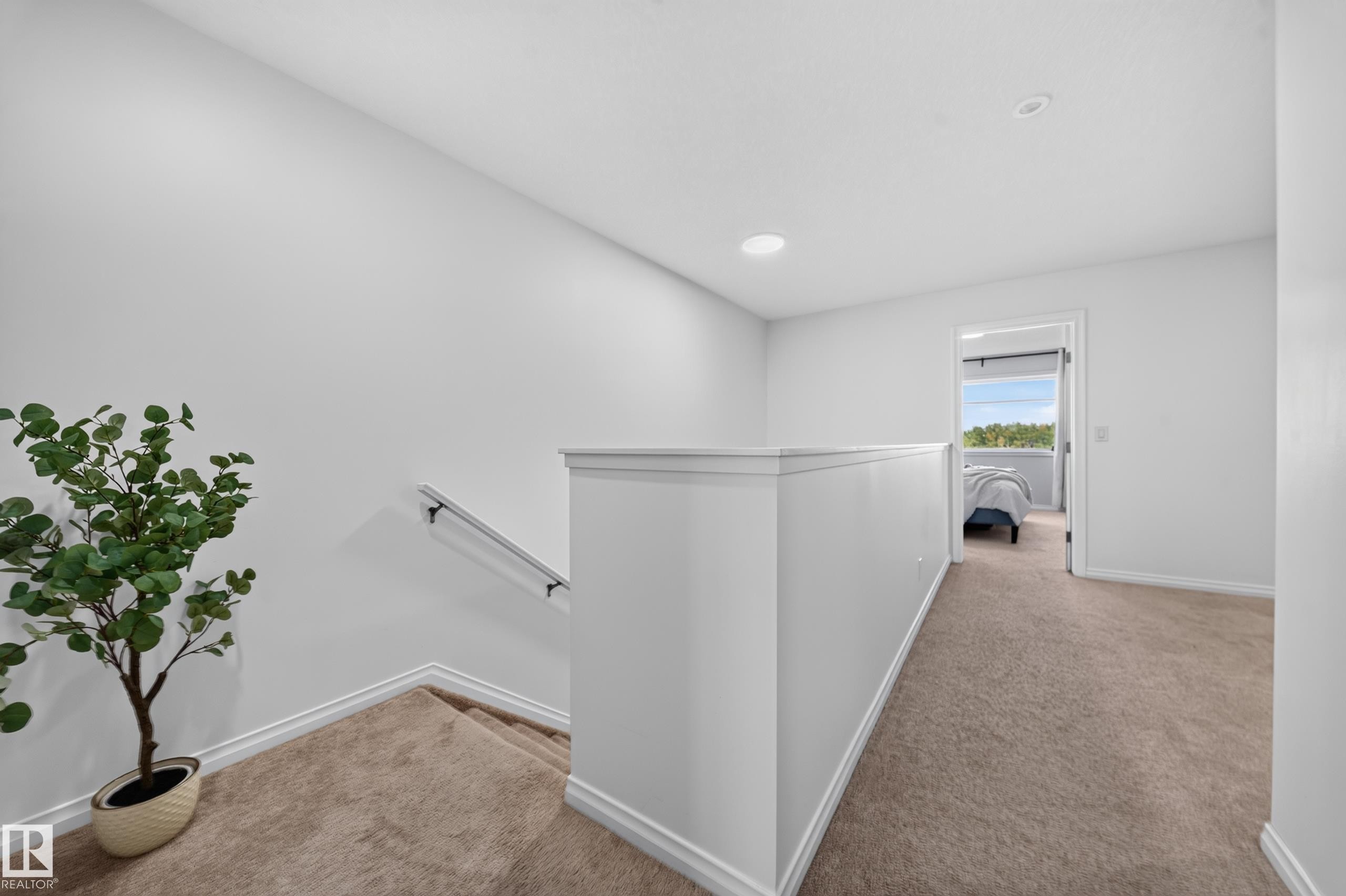 Carpeted landing with white balustrade, recessed lighting, and a metal handrail - 4104 3 Avenue Sw, Edmonton, AB