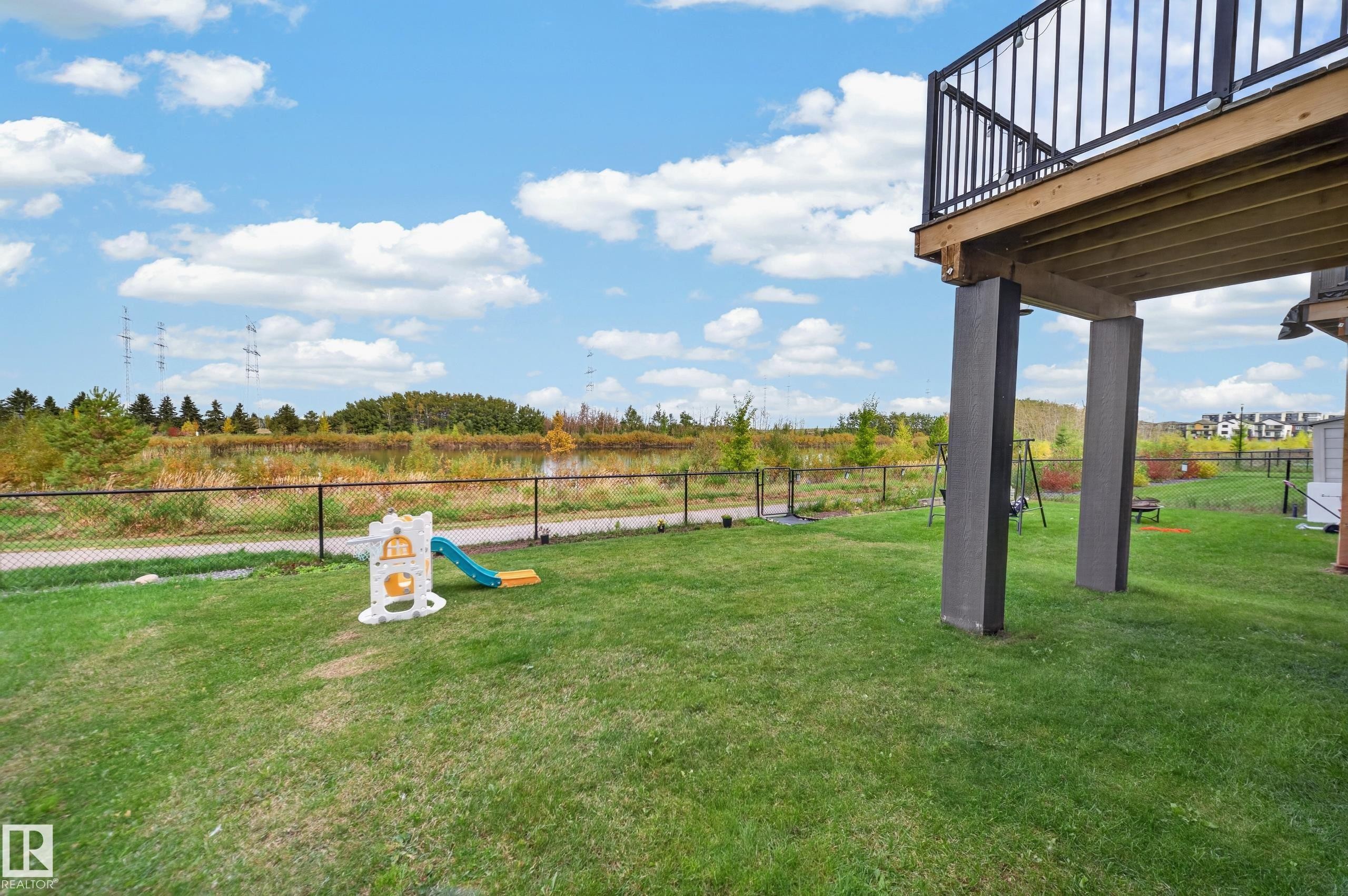 Expansive green lawn with a black chain-link fence and a raised wooden deck with black railings - 4104 3 Avenue Sw, Edmonton, AB