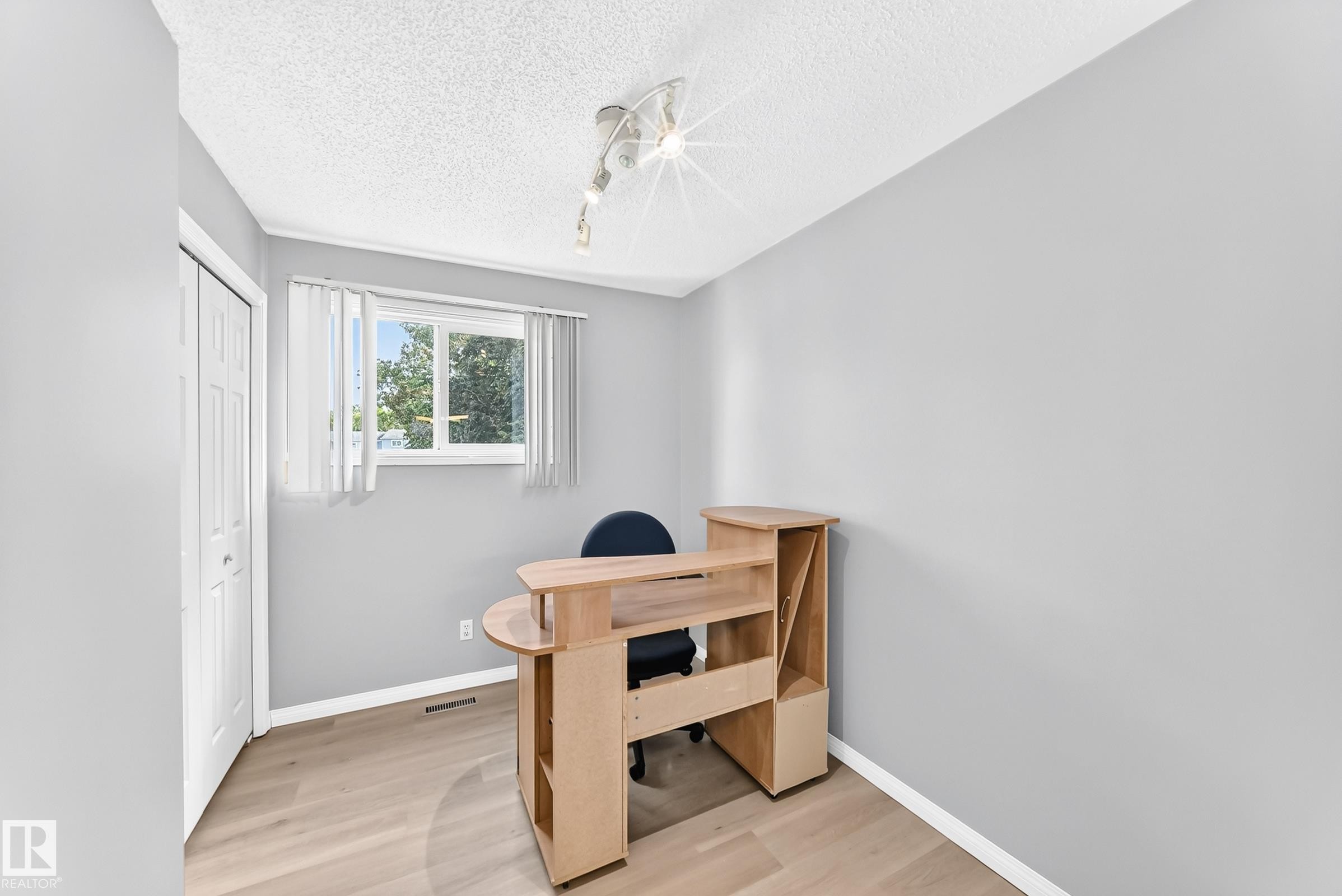 Light gray walls with white trim, wood-finish flooring, a window with vertical blinds, and a bi-fold closet door - 44 Habitat Crescent Nw, Edmonton, AB