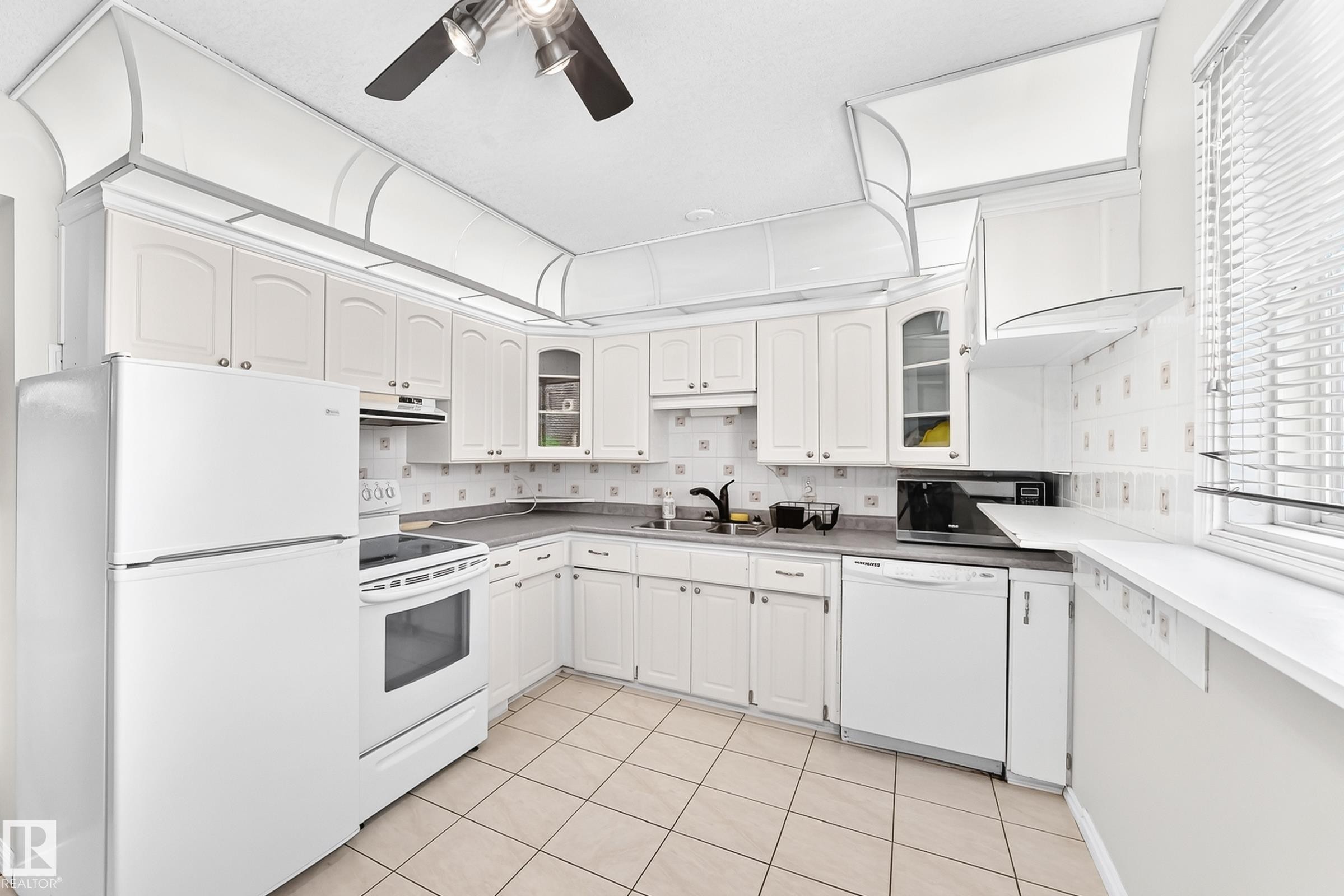 Kitchen featuring white cabinetry, tile flooring, and integrated white appliances - 44 Habitat Crescent Nw, Edmonton, AB