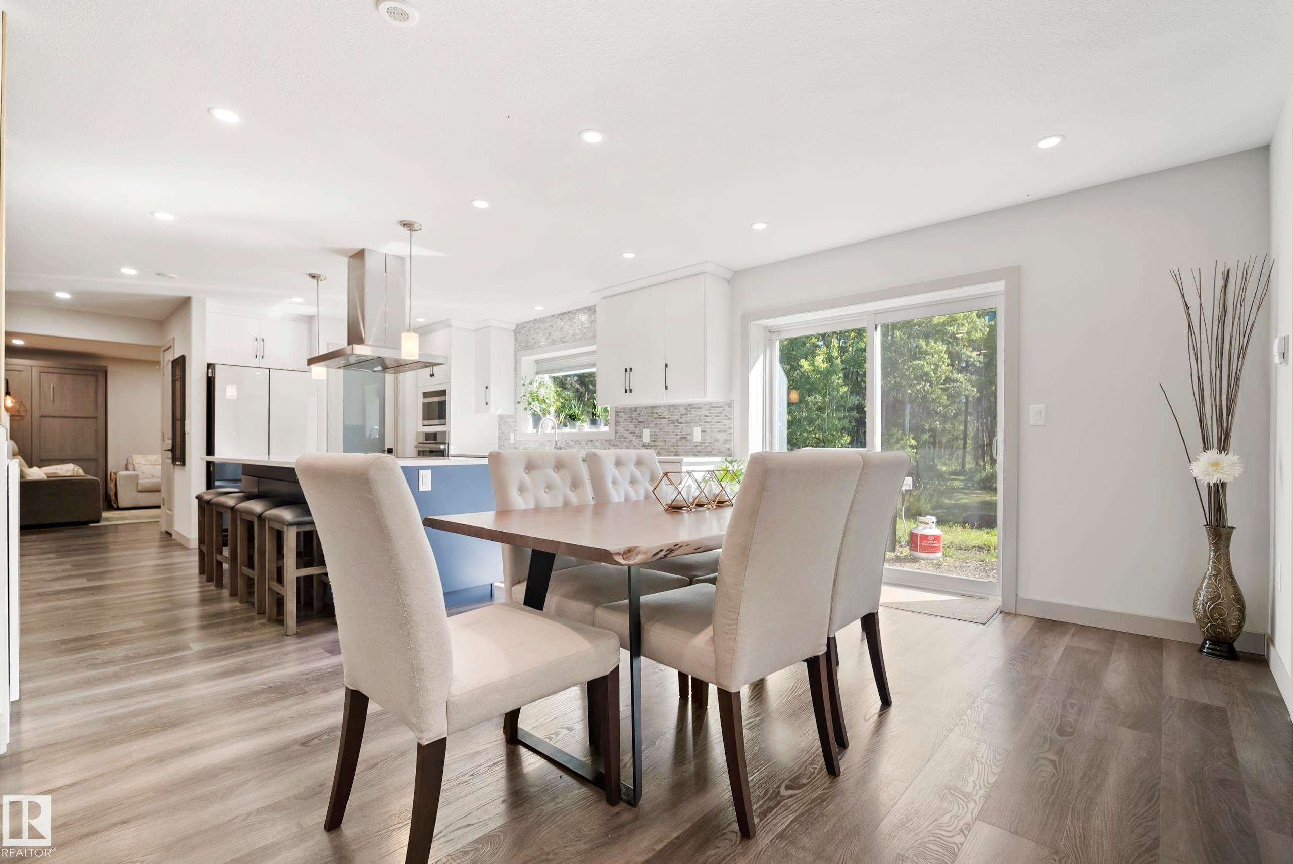Recessed lighting throughout, wood-finish flooring, sliding glass door, kitchen island with seating, stainless steel appliances - 49279 Rge Rd 240, Rural Leduc County, AB