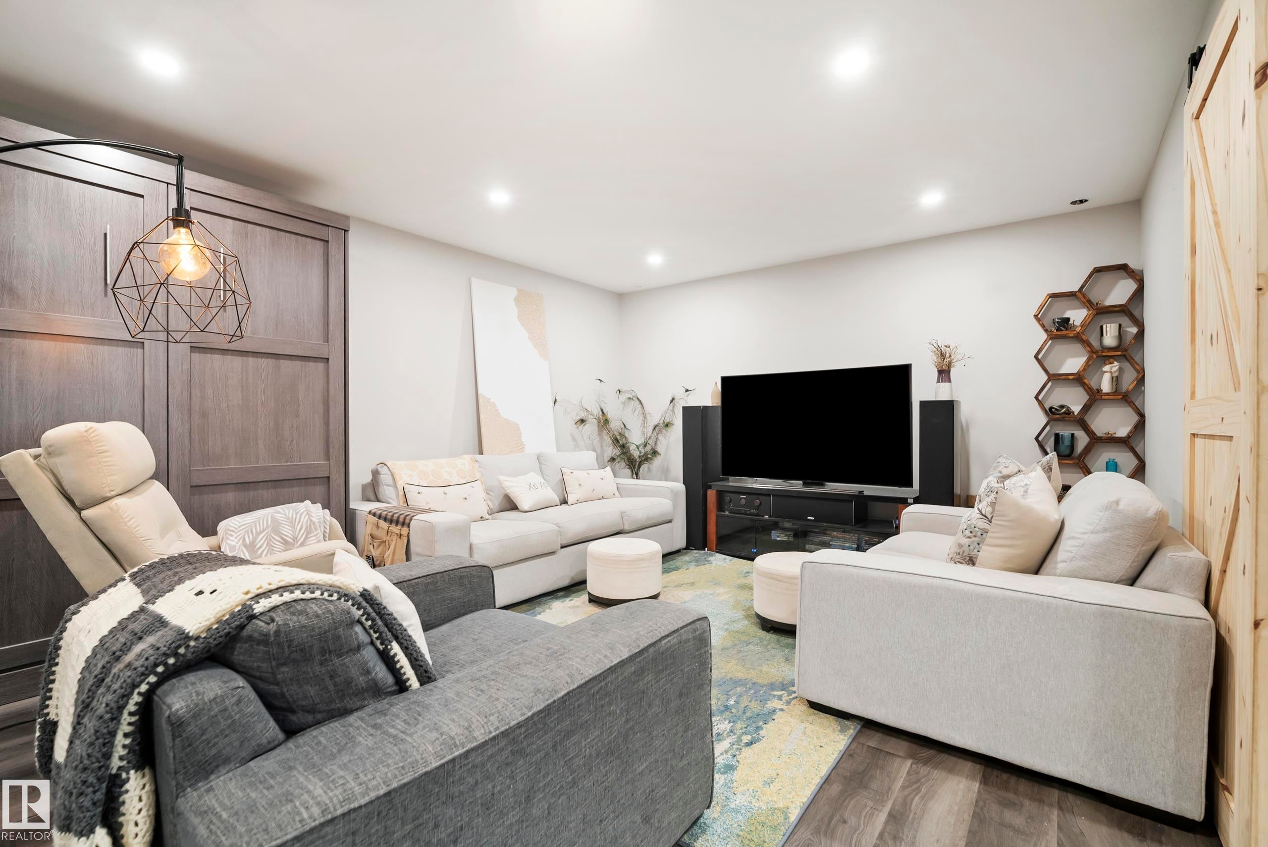 Recessed lighting, wood-finish flooring, accent wall with built-in cabinetry, modern geometric pendant light, and rustic wood barn door - 49279 Rge Rd 240, Rural Leduc County, AB