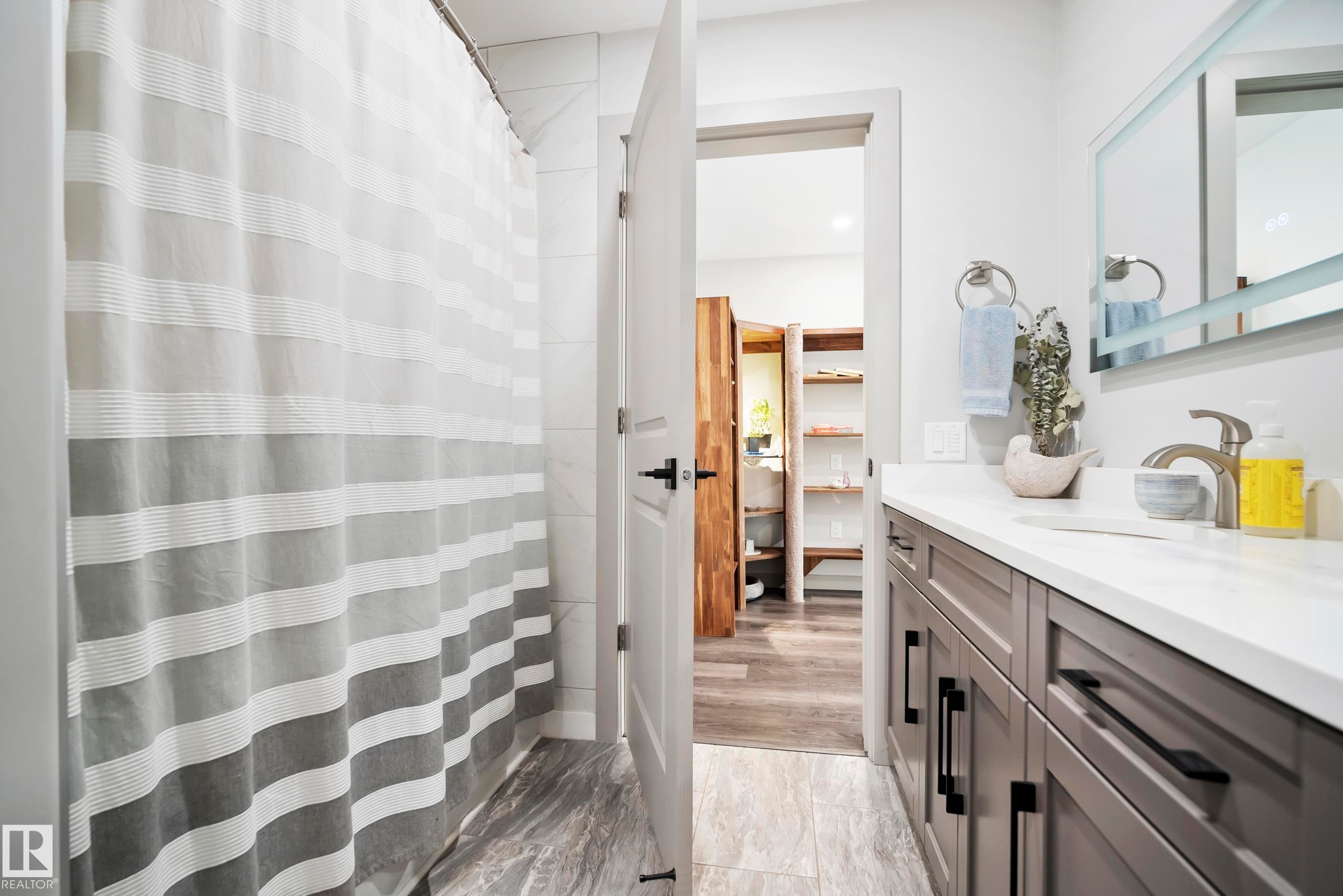 Bathroom featuring a vanity with an integrated sink, satin nickel faucet, and under-mirror lighting - 49279 Rge Rd 240, Rural Leduc County, AB