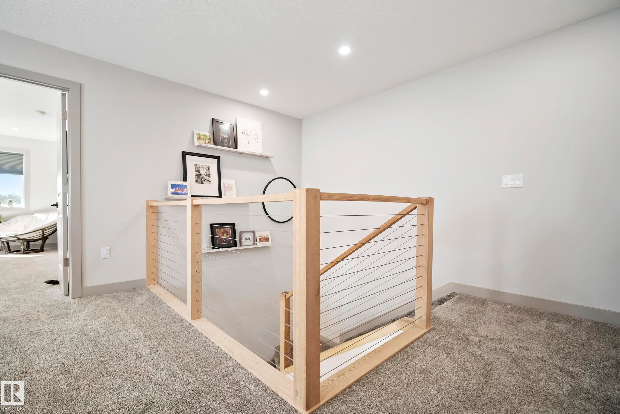 Carpeted landing featuring a wooden and cable railing system, recessed lighting, and built-in floating shelves - 49279 Rge Rd 240, Rural Leduc County, AB