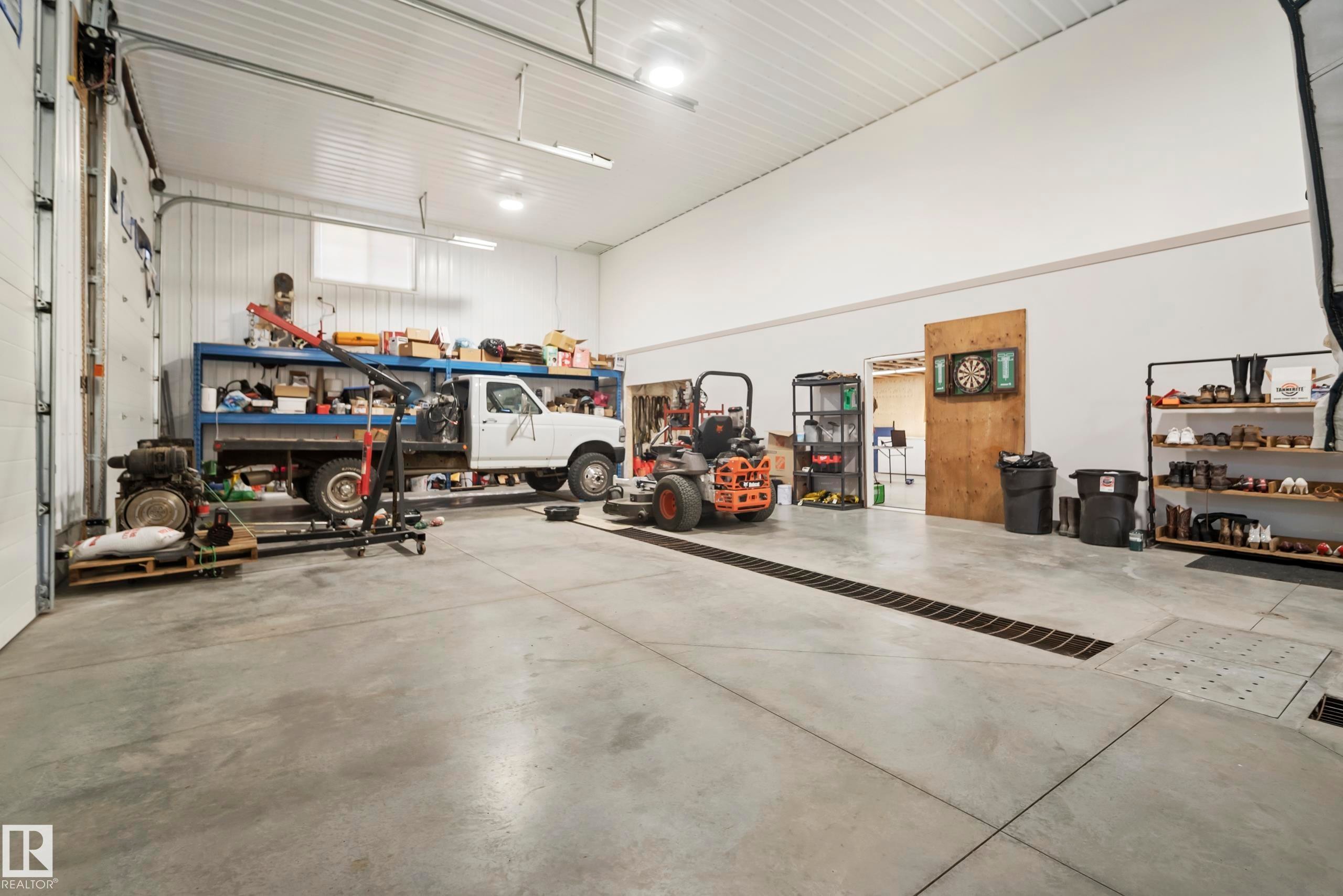 Spacious concrete floor garage with high ceilings, fluorescent lighting, and large overhead doors - 49279 Rge Rd 240, Rural Leduc County, AB