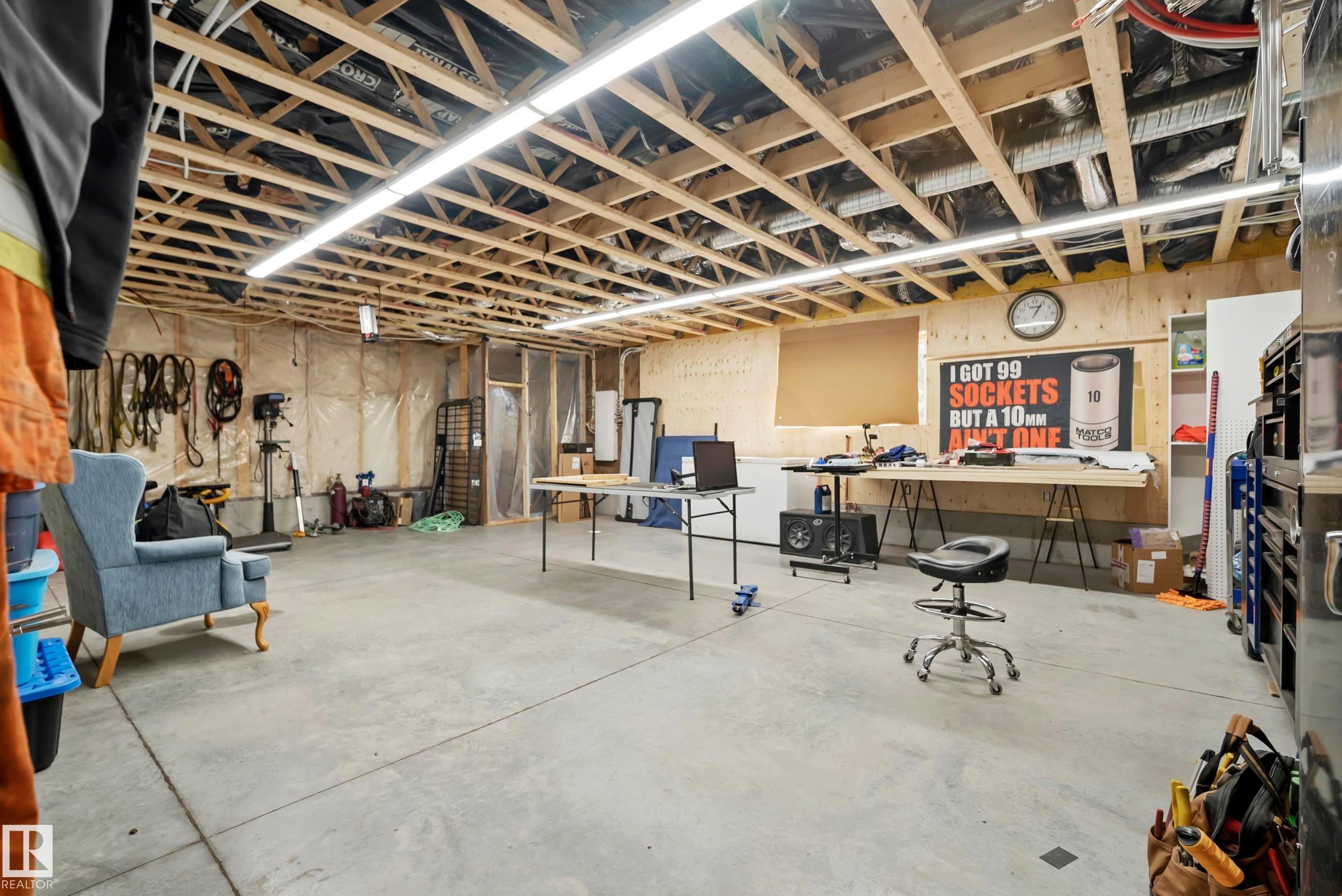 Exposed ceiling joists, concrete flooring, wood-paneled accent wall, and perimeter wall insulation - 49279 Rge Rd 240, Rural Leduc County, AB